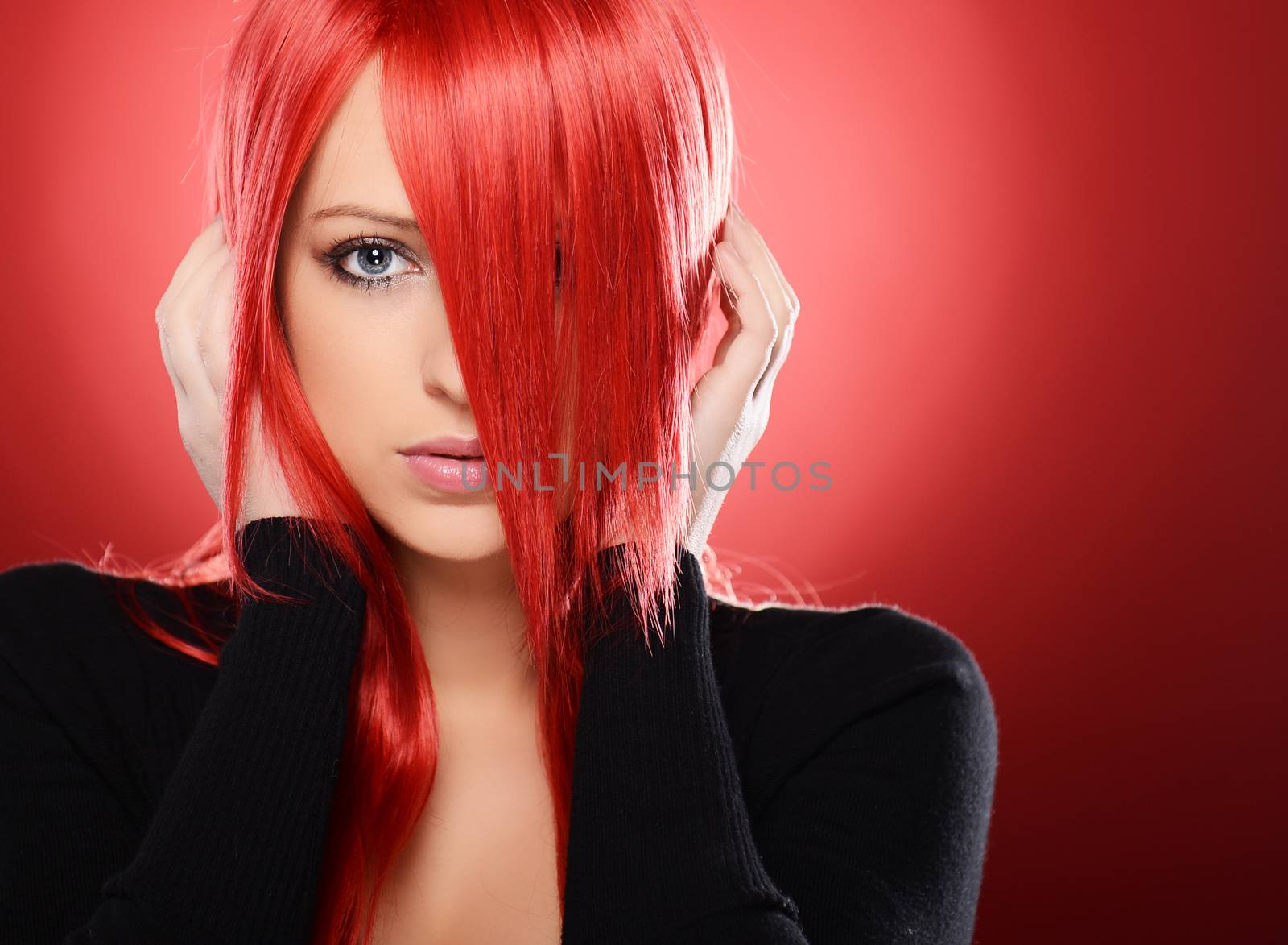 Beautiful red haired woman posing over red background