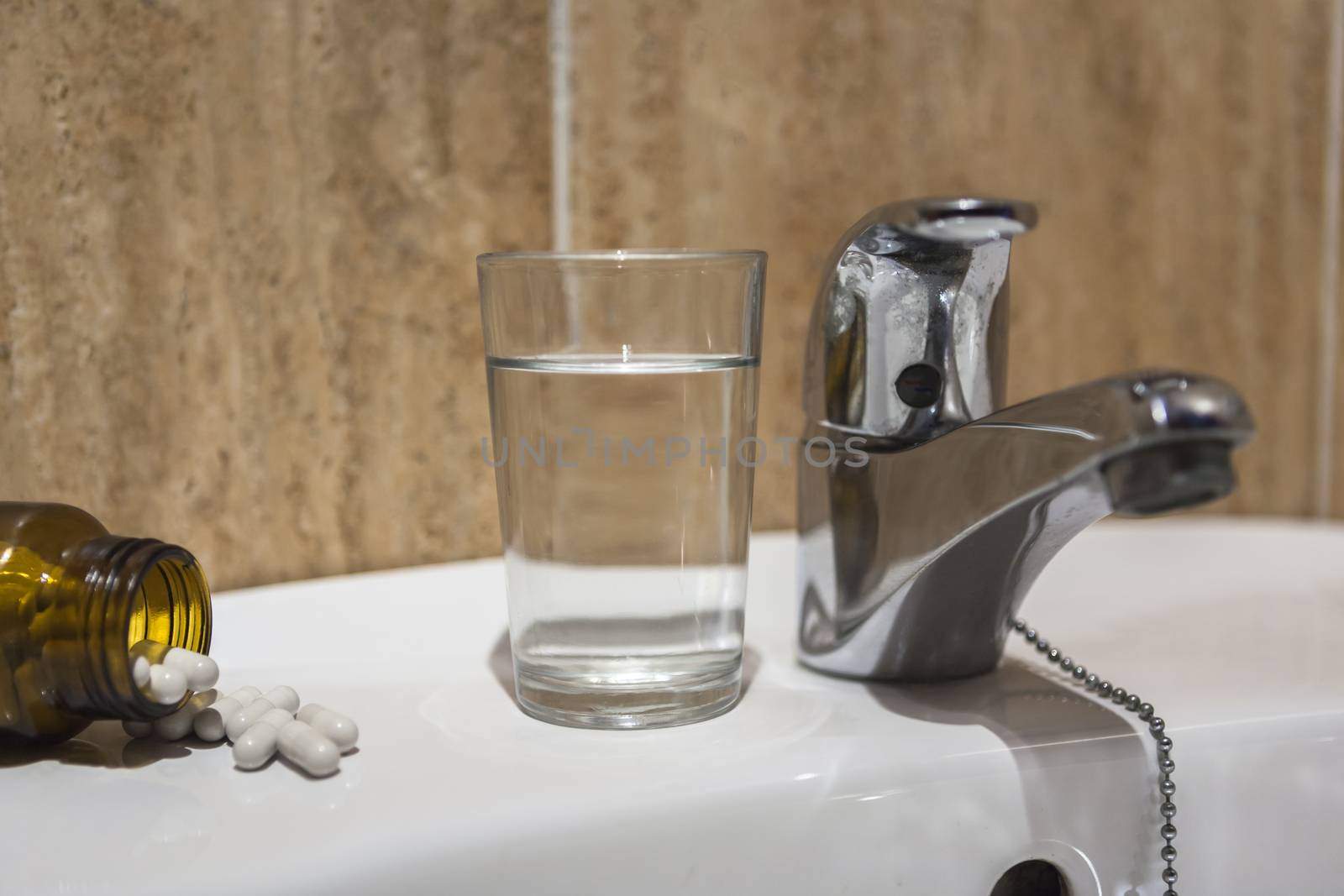 Glass of water and pile of blister packs in bathroom shelf