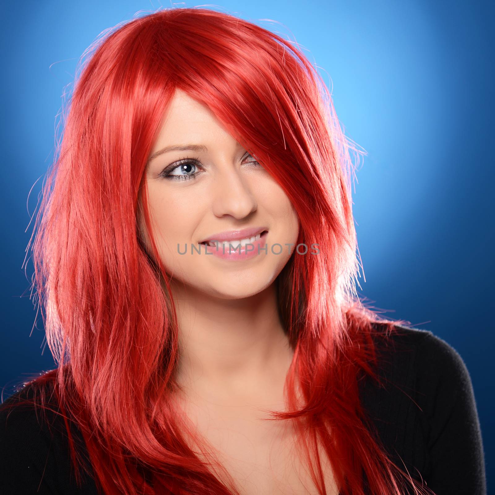 Beautiful red haired woman posing over blue background