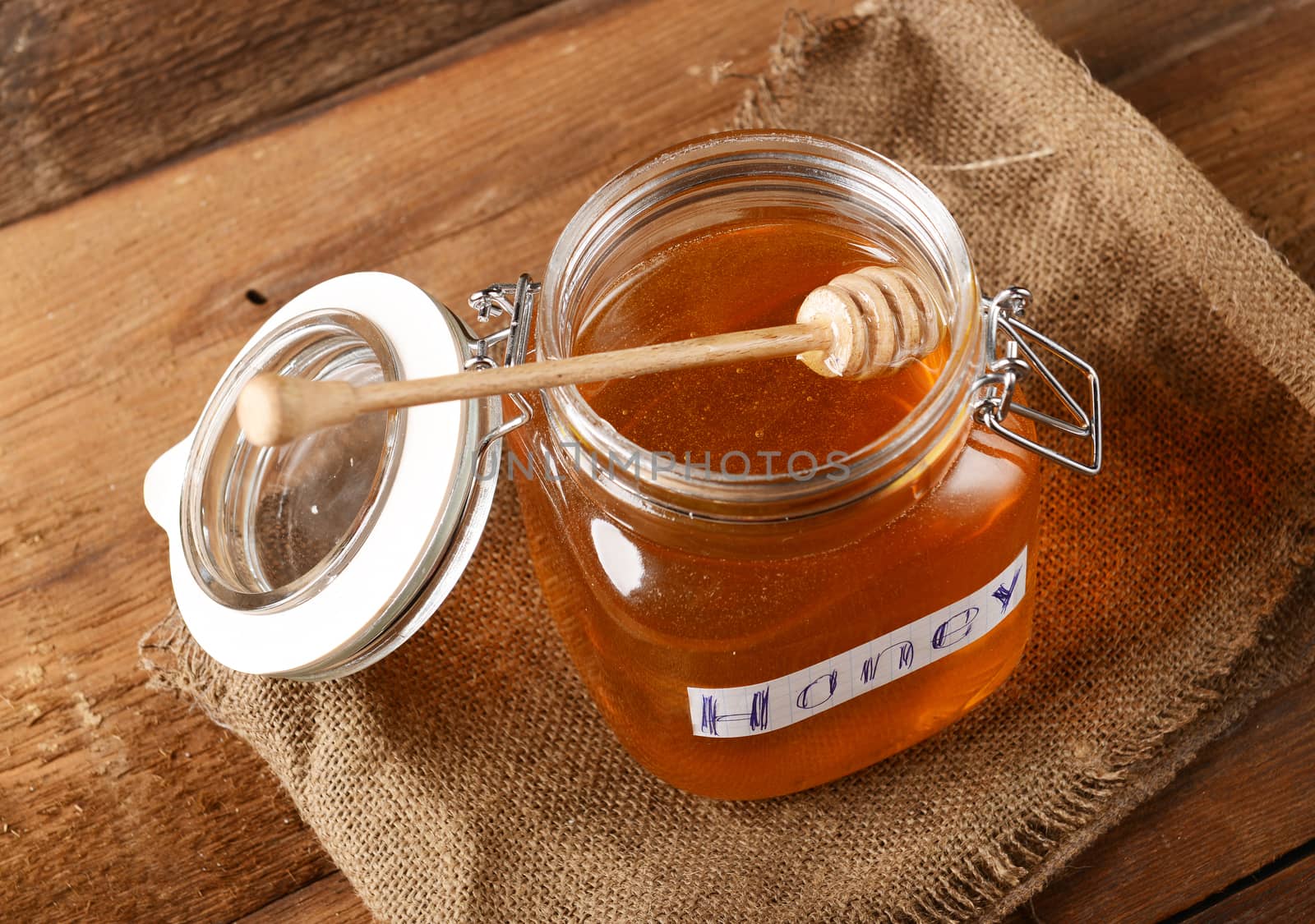 Fresh honey in glass jar on wooden background
