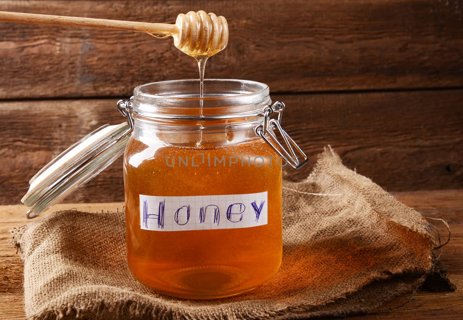 Fresh honey in glass jar on wooden background