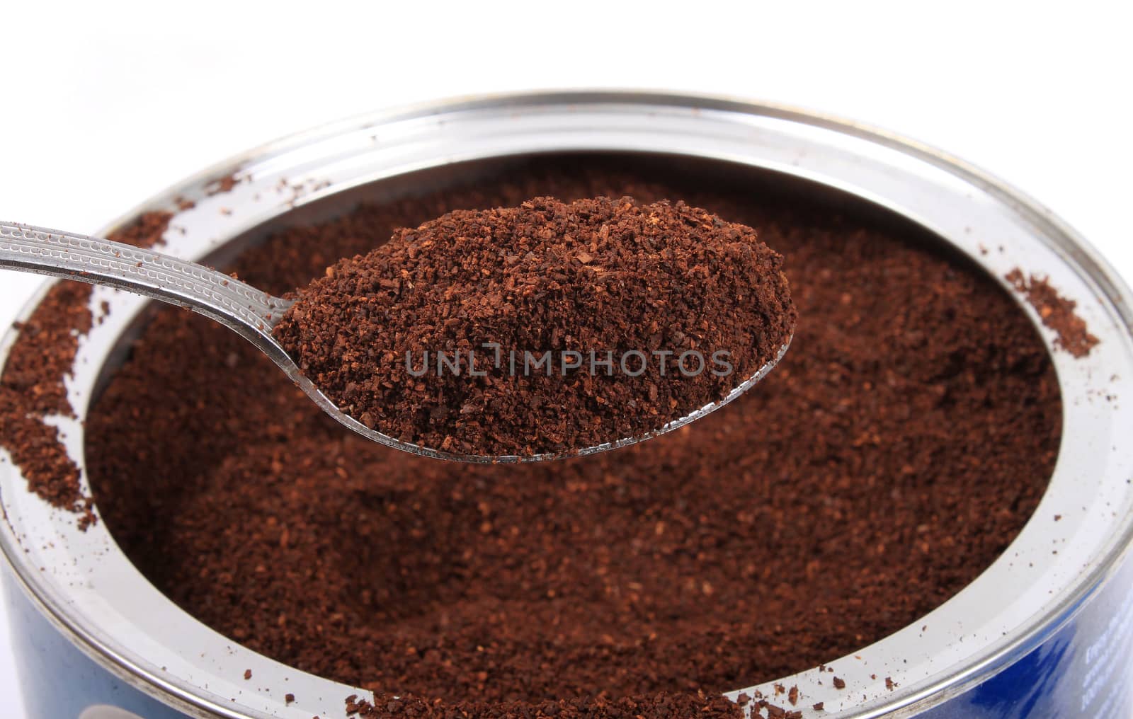 Spoonfull of fresh ground coffee in a can on a white background