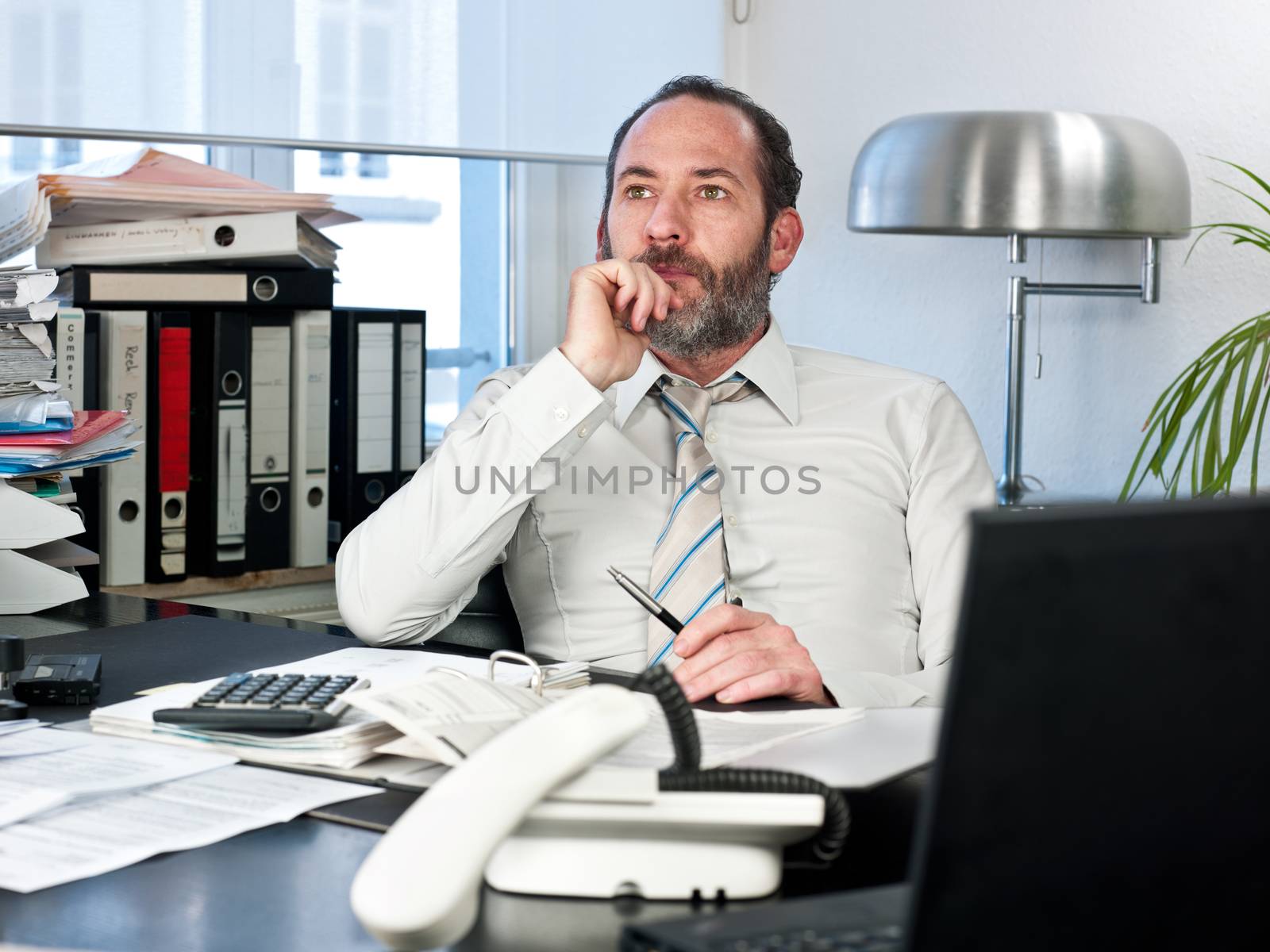 Contemplative businessman looking away at work. Horizontal shot