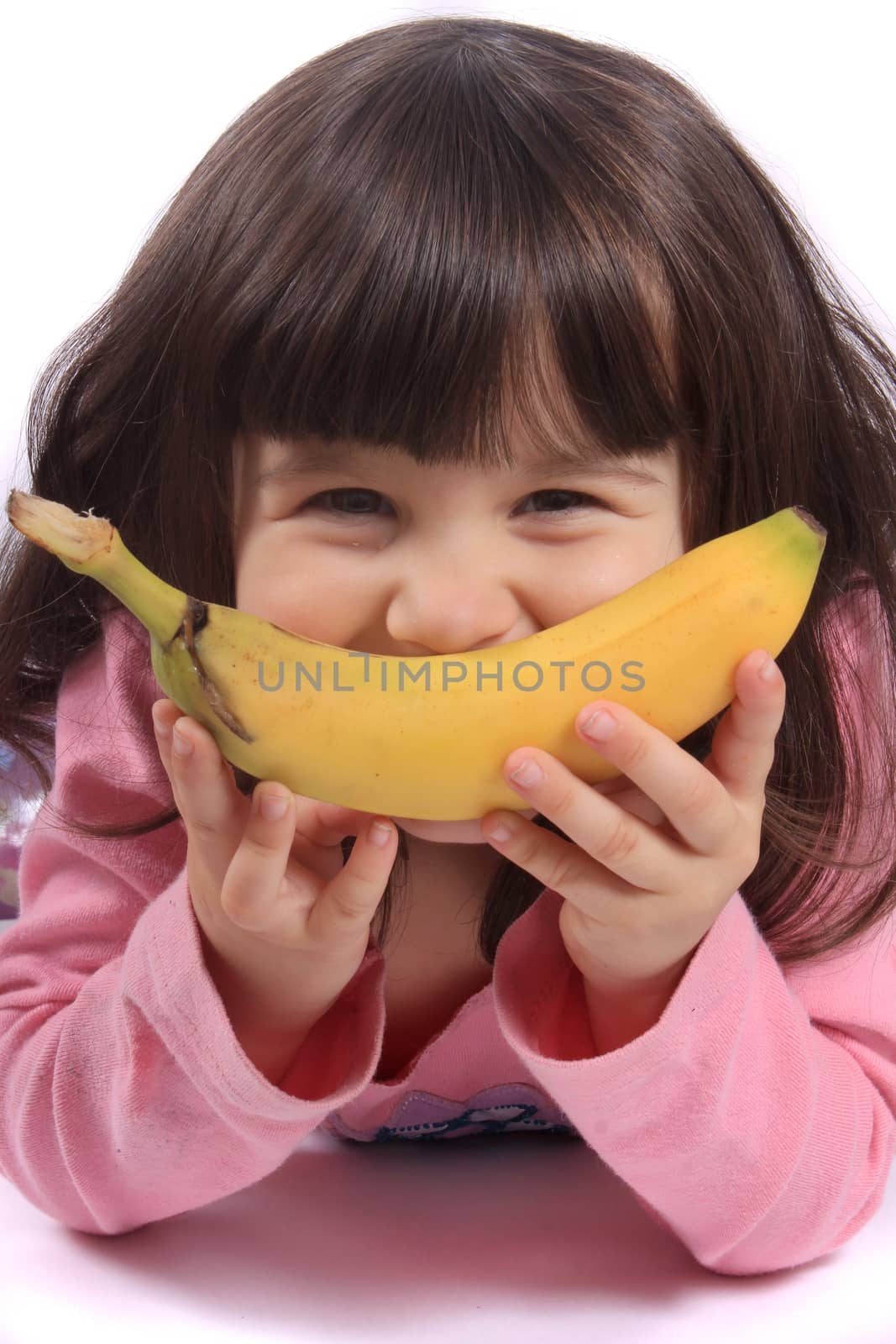 Young little girl making a funny face with a banana as her smile