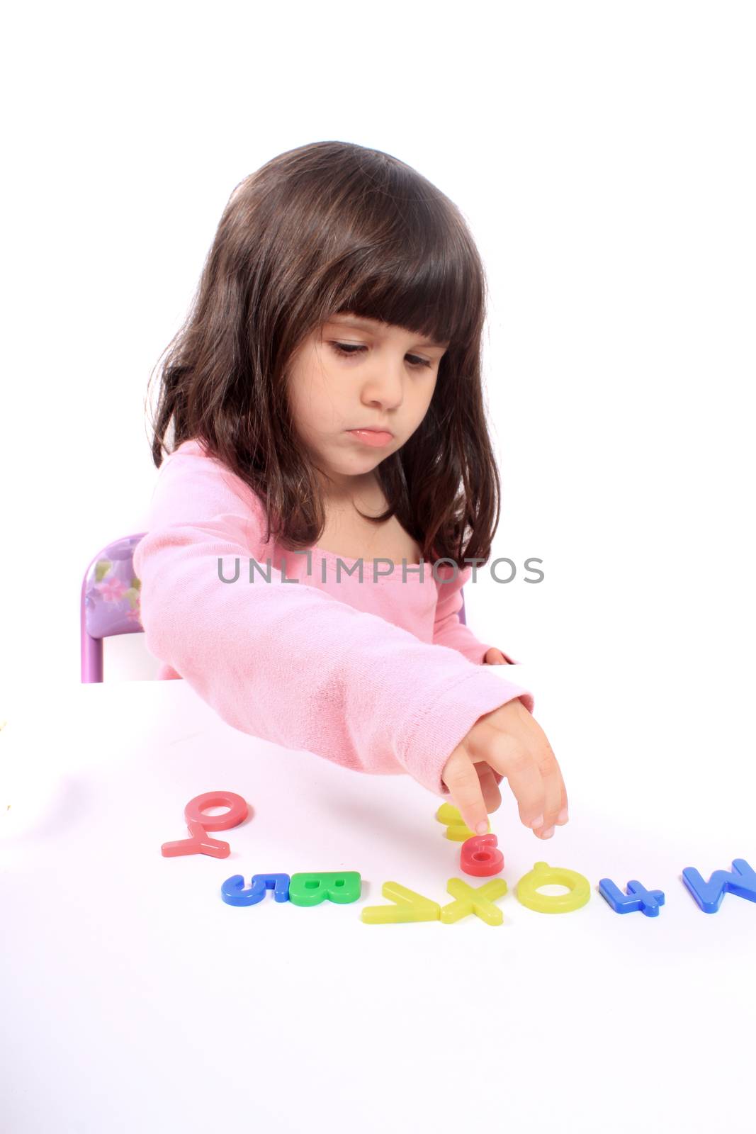 Young little preschool girl with funny expression playing with letters and numbers