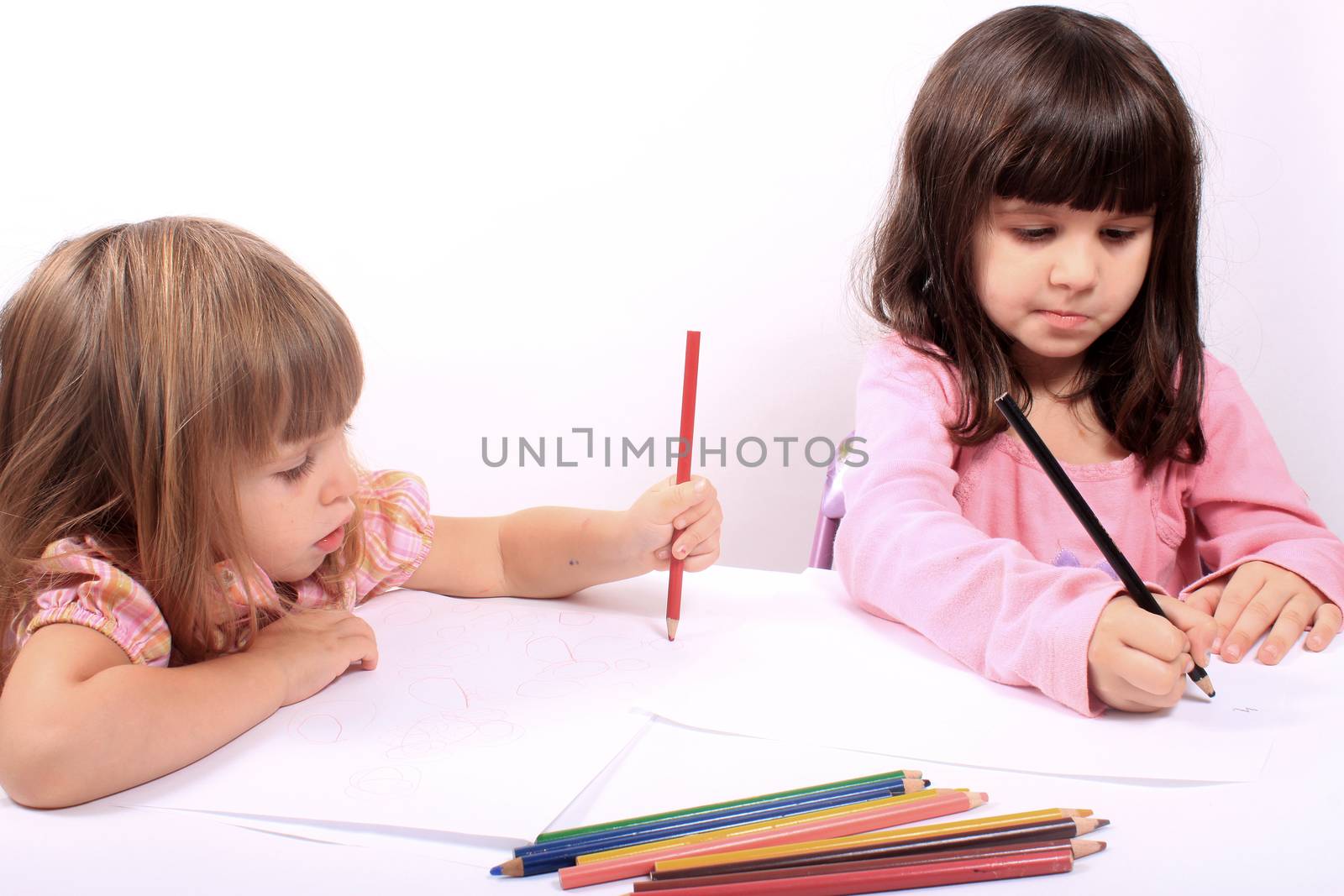 Two little preschool girls drawing with colorful pencil crayons