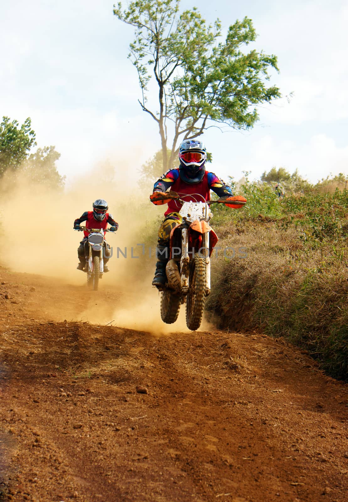 The motorcycle race hole on December at Dambri waterfall, motorcyclist try to speed up goal, red soil way, indistinct dust