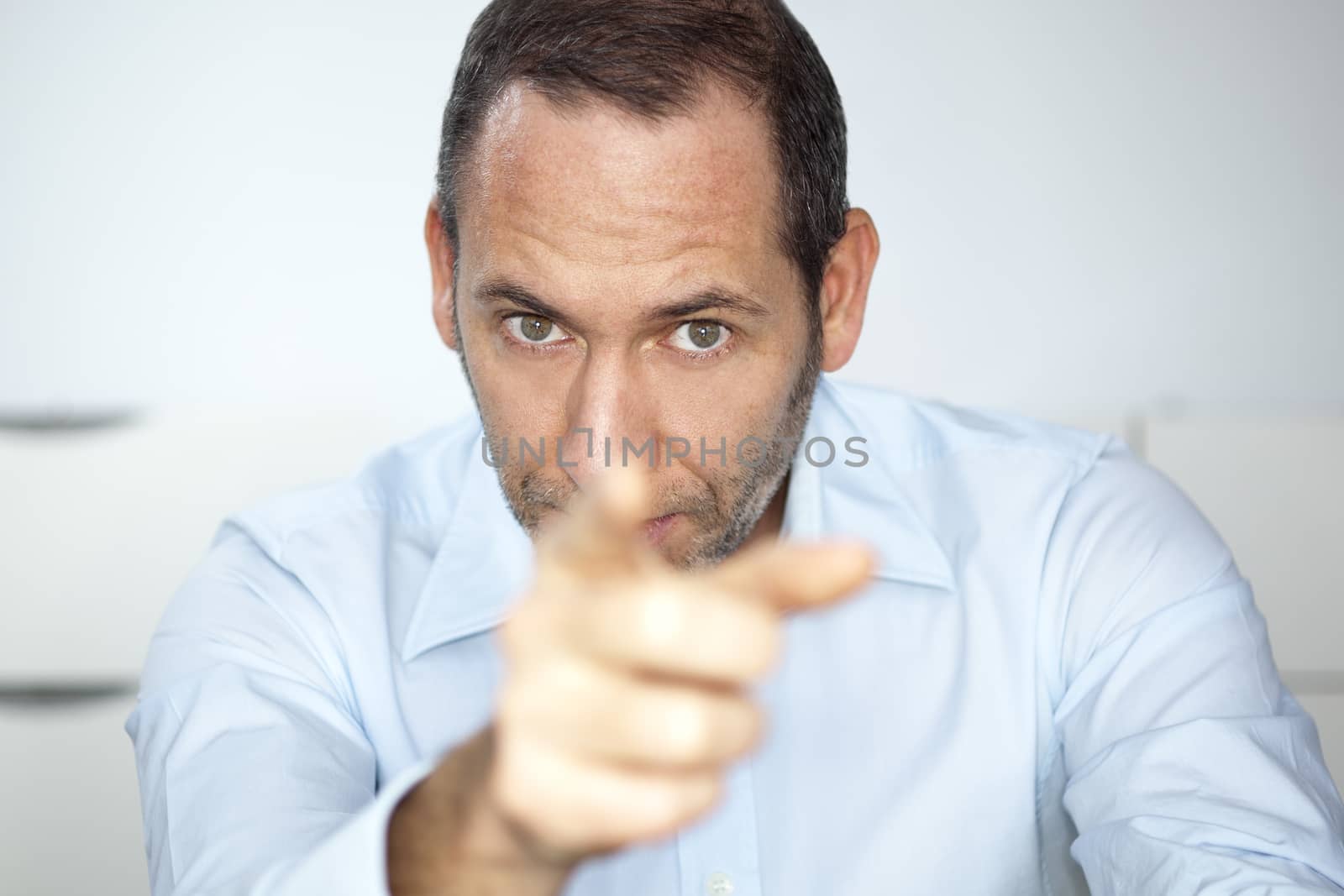 mature well dressed businessman is pointing into the camera