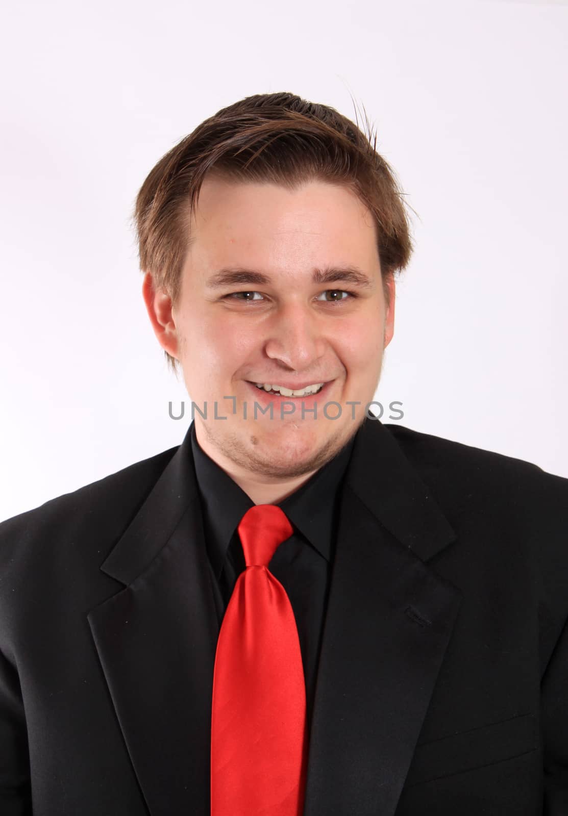 Handsome smiling, young businessman in black formal suit with red tie