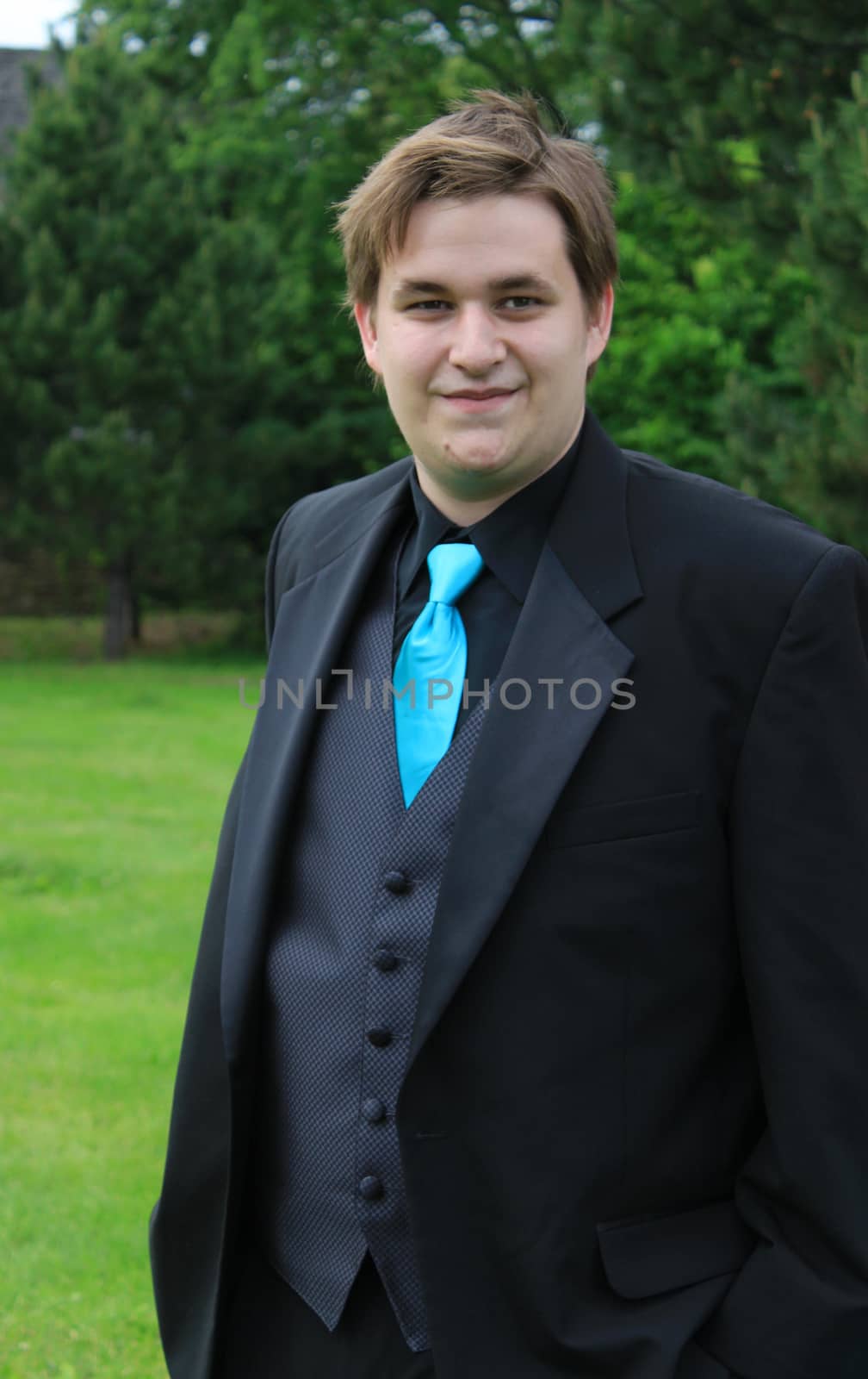 Handsome, smiling young man wearing a formal suit going to the prom or a groom at a wedding