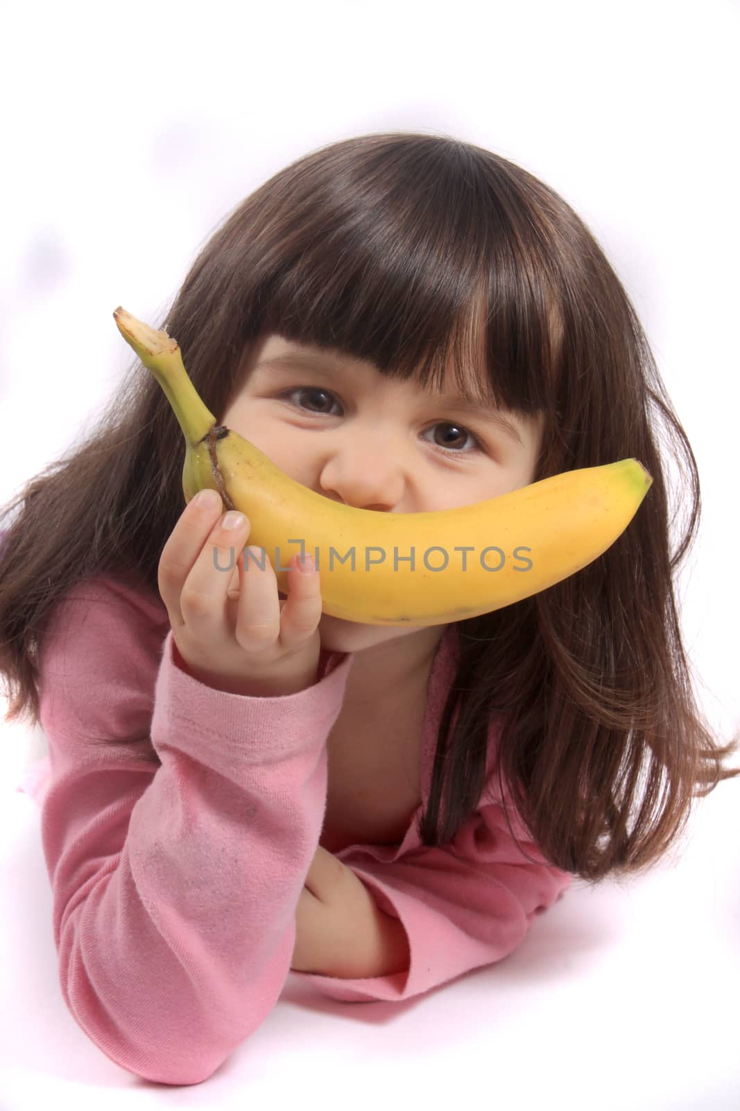 Young little girl making a funny face with a banana as her smile
