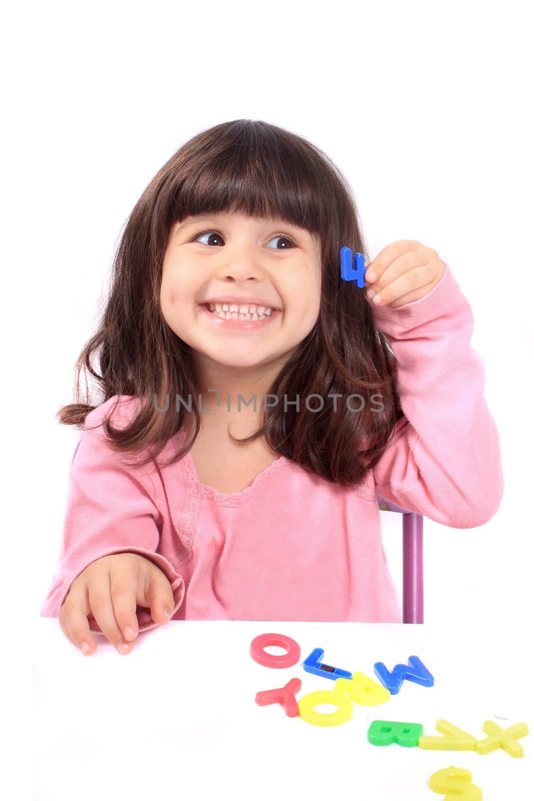 Young little preschool girl with funny expression playing with letters and holding up the number four showing her age