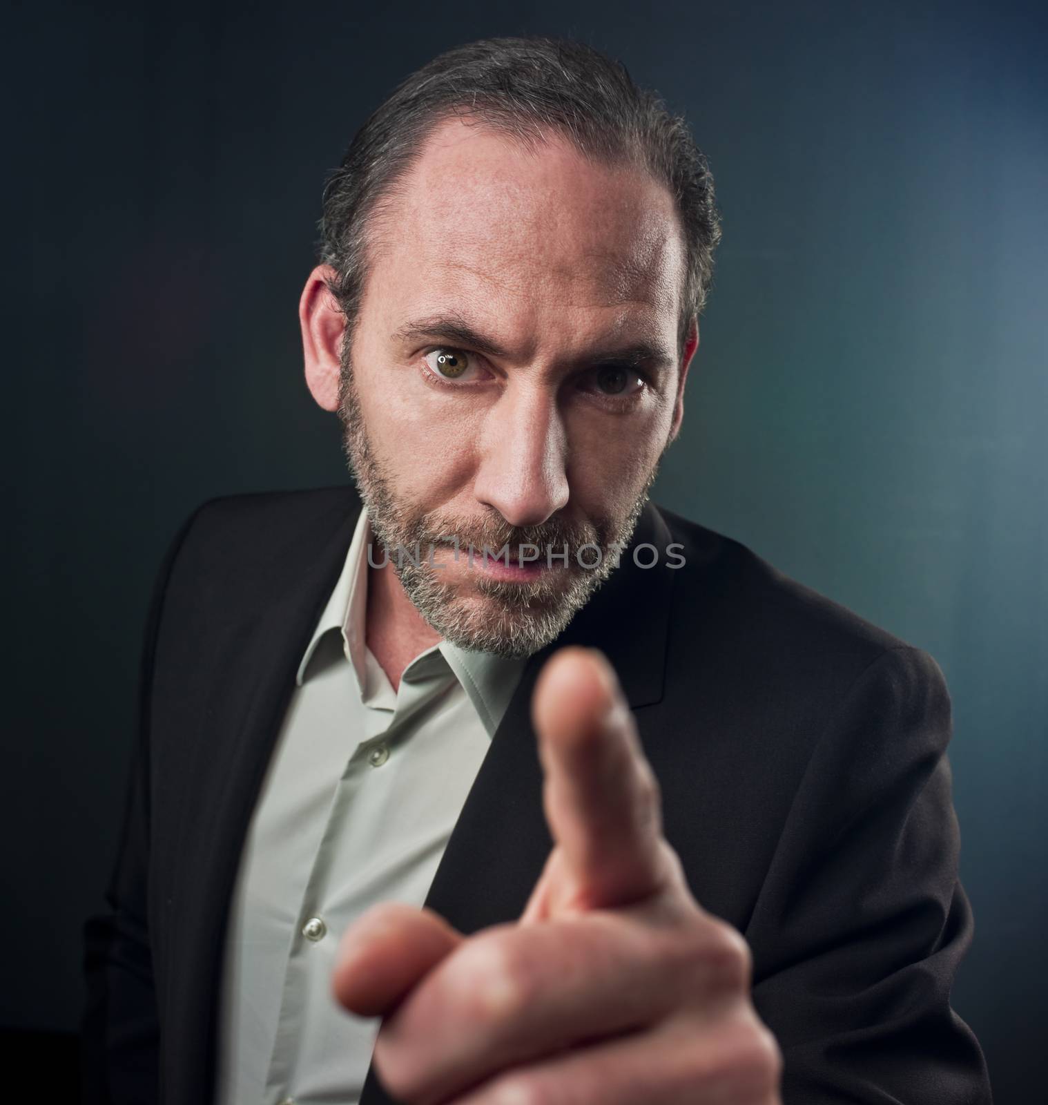Portrait of mature businessman pointing at you over colored background (shot on PhaseOne 45)