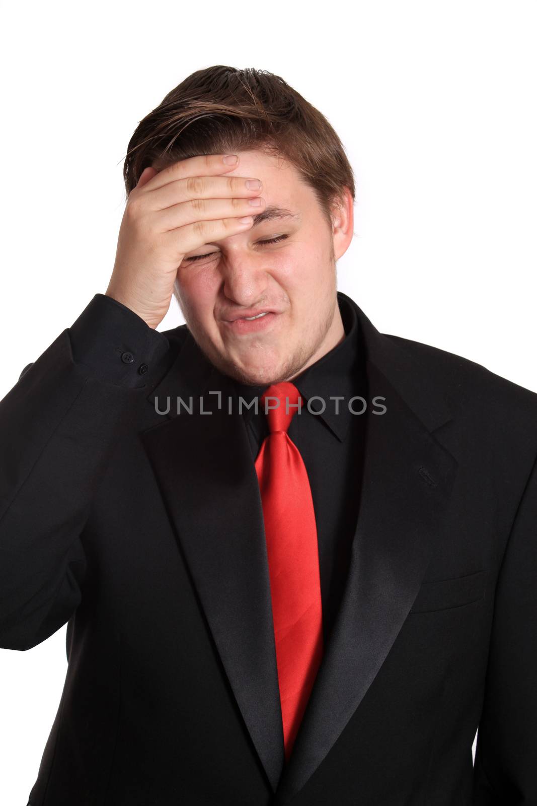 Young stressed business man with headache wearing a black formal suit and red tie on a white background