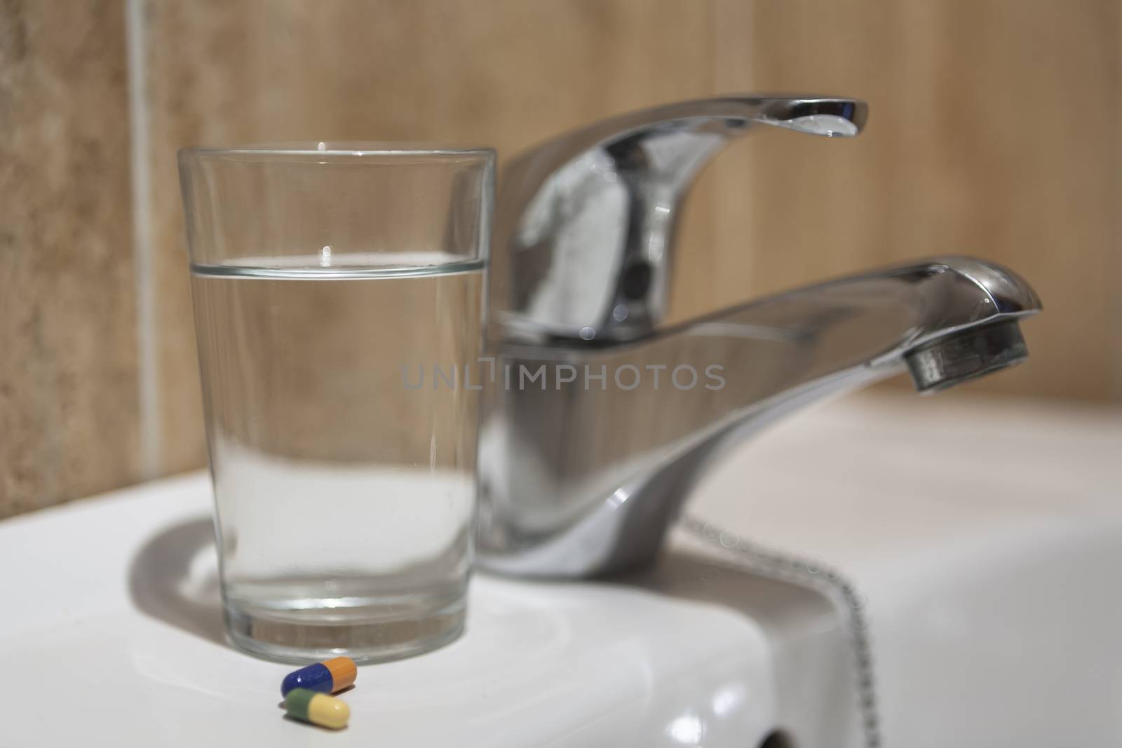 Glass of water and pile of blister packs in bathroom shelf