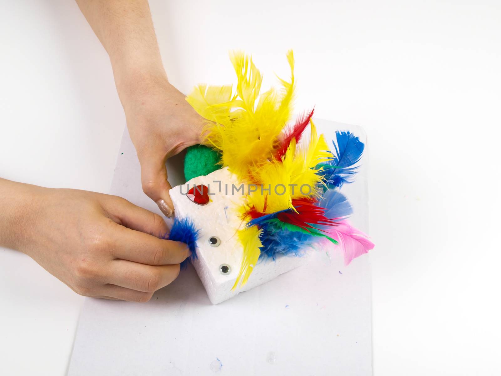 Little girls hands playing with colorful feathers, creating Easter decoration