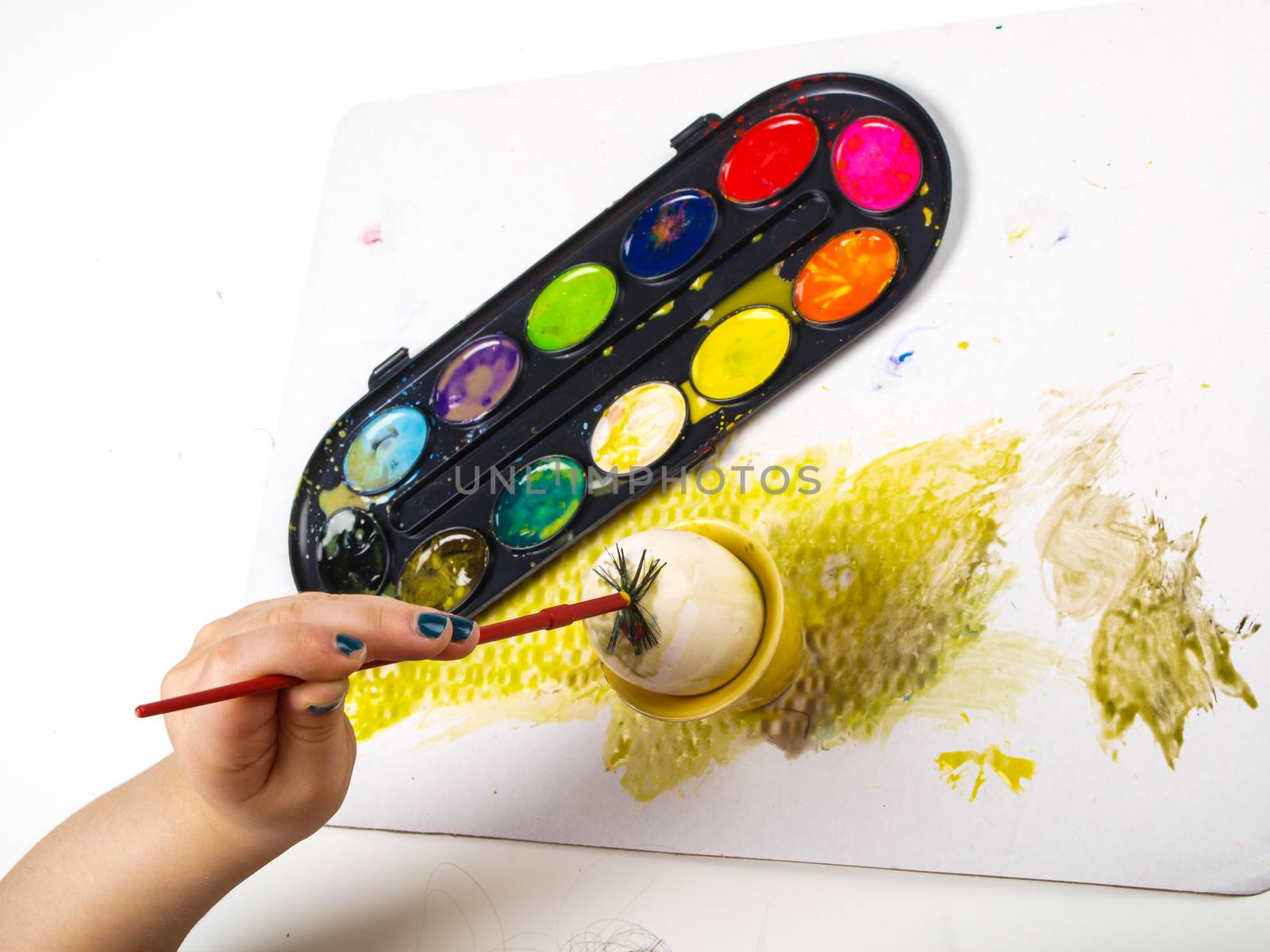 Little girls hands playing with colorful paint, creating Easter decoration