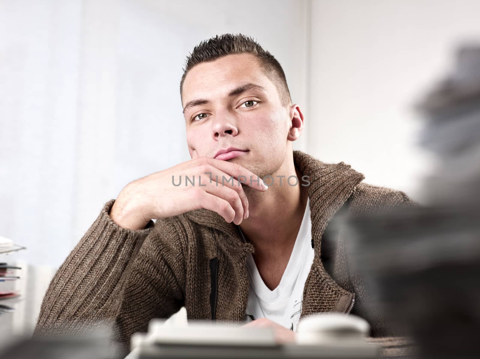 Young handsome businessman thinking at office. Horizontal shot