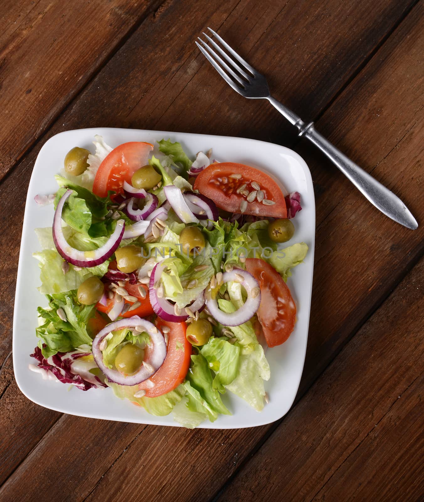 Salad with tomatoes and olives on wooden background