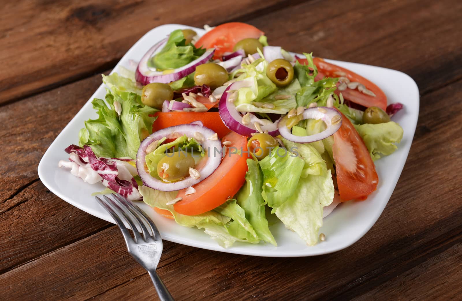 Salad with tomatoes and olives on wooden background