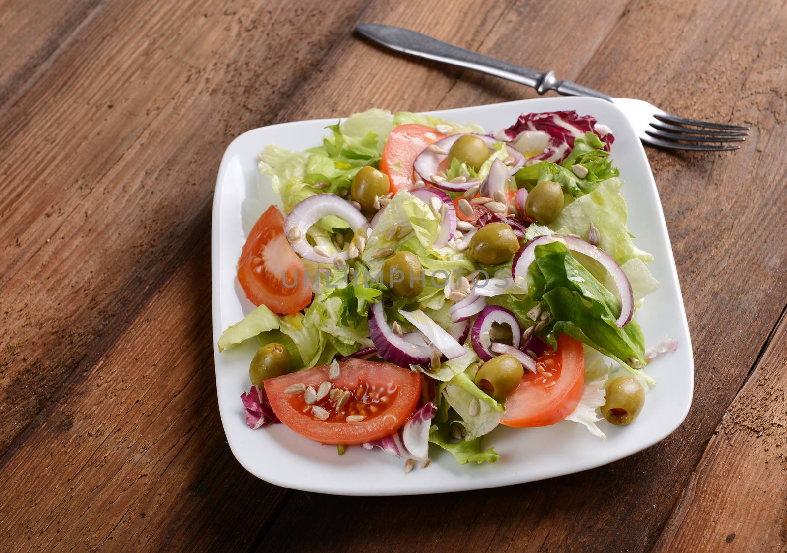 Salad with tomatoes and olives on wooden background