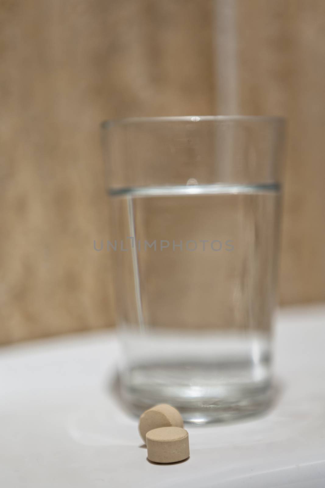 Glass of water and pills in bathroom shelf