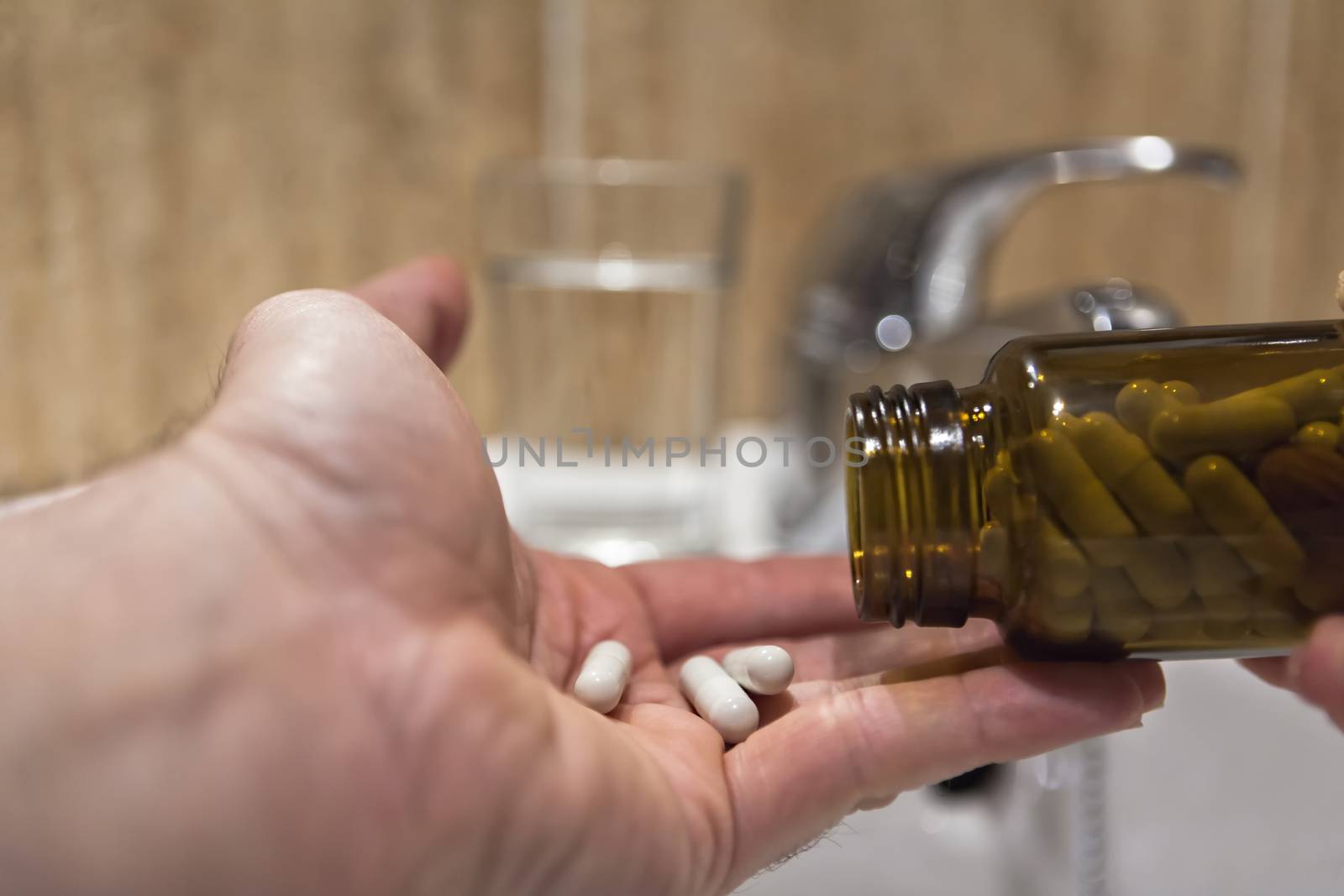 Hand spilling pills for the pain of a bottle in the bathroom by digicomphoto