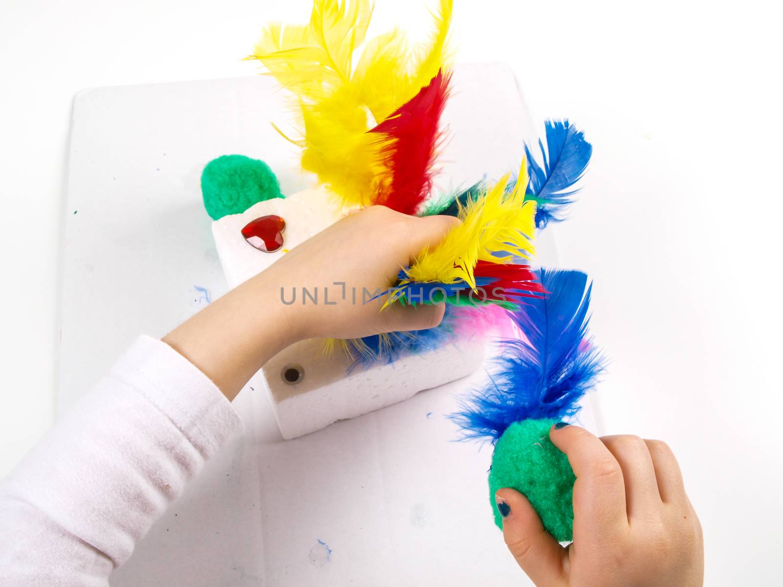 Little girls hands playing with colorful feathers, creating Easter decoration