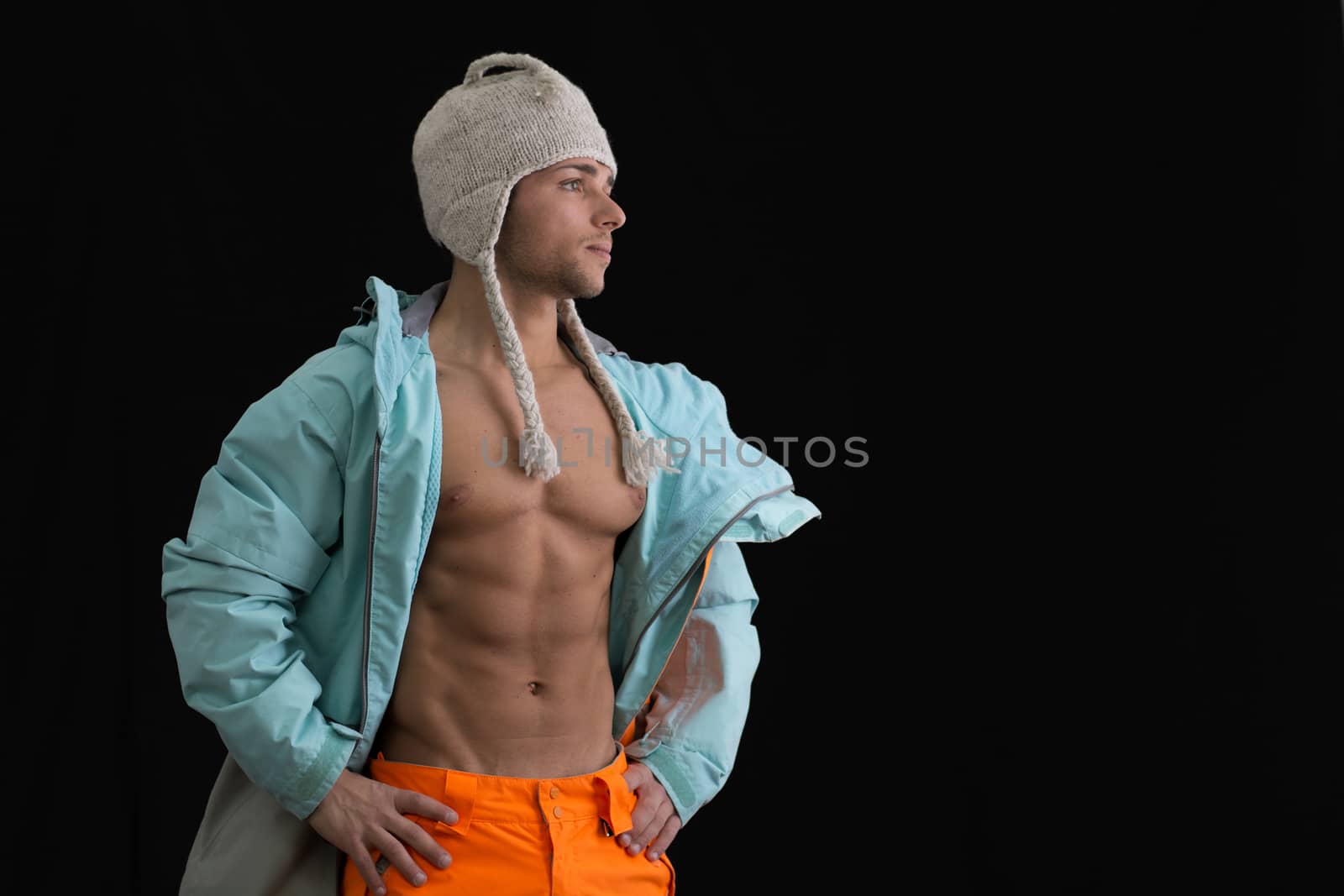 Attractive young male skier or snowboarder with open coat on naked muscular torso