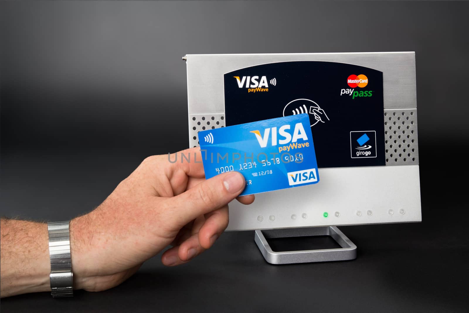 Aachen, Germany - August 05, 2012: Studioshot of payment action with the Visa Paywave credit card in front of a NFC terminal wich accepts visa, mastercard, american express and girogo contactless payments.