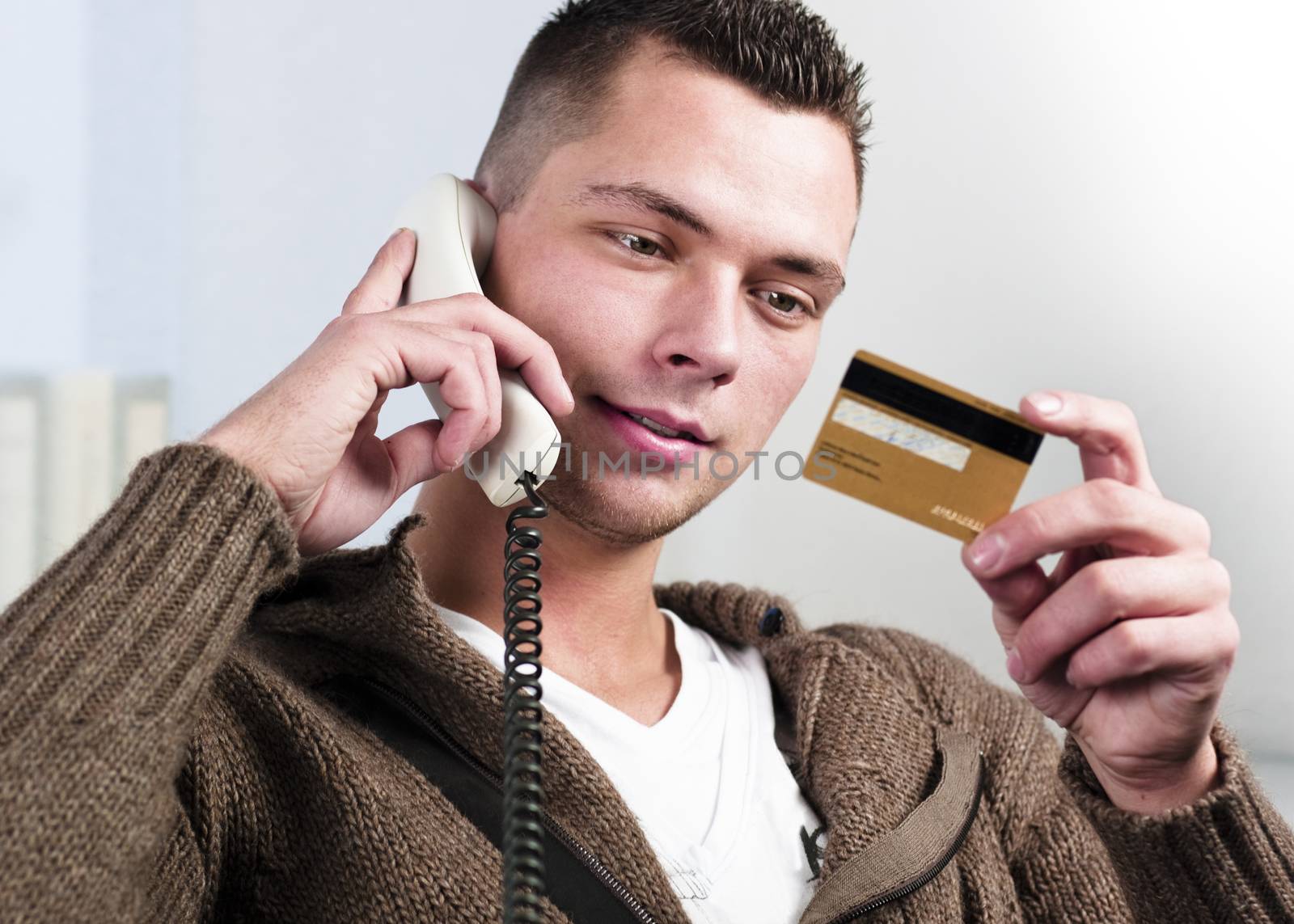 Smiling young businessman having conversation on landline phone. Horizontal shot