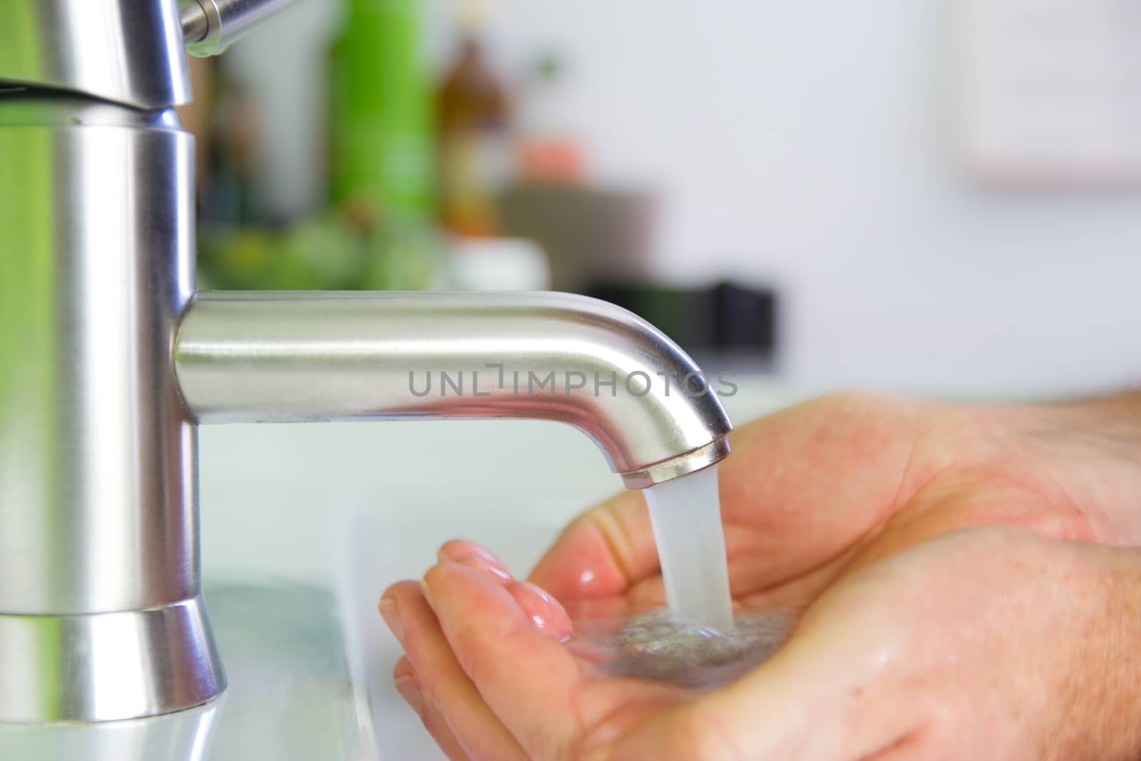 holding hand under sparkling fresh water out of the faucet