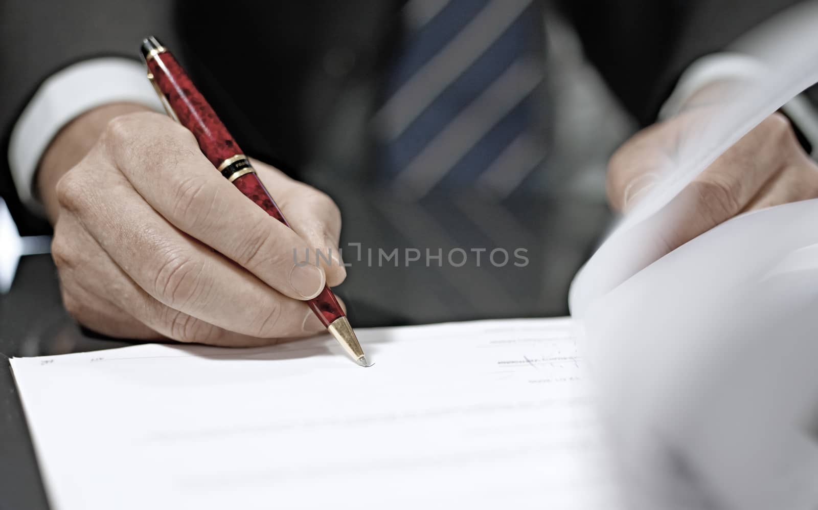 Businessman sitting at shiny office desk signing a contract with noble pen 