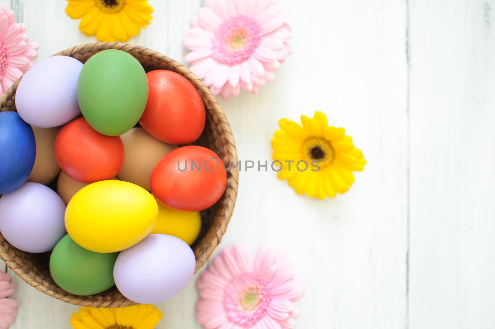 Easter eggs inside a wicker basket with daisies