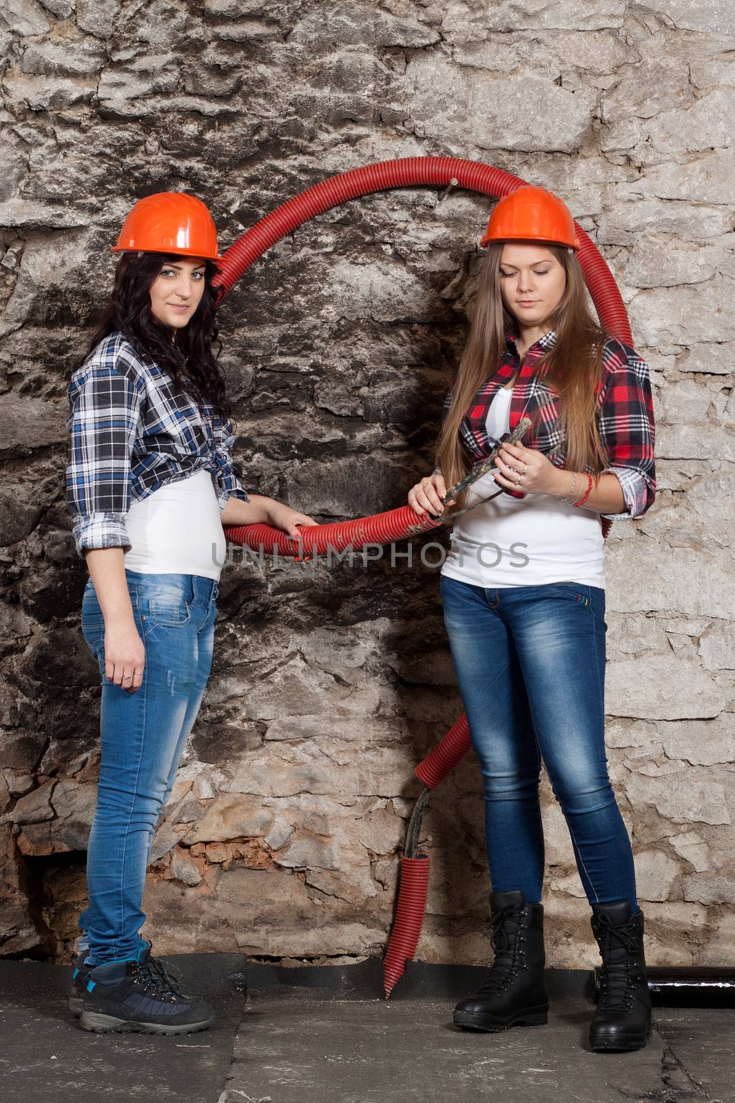 Two young long-haired woman looking cables for the repair of an old house