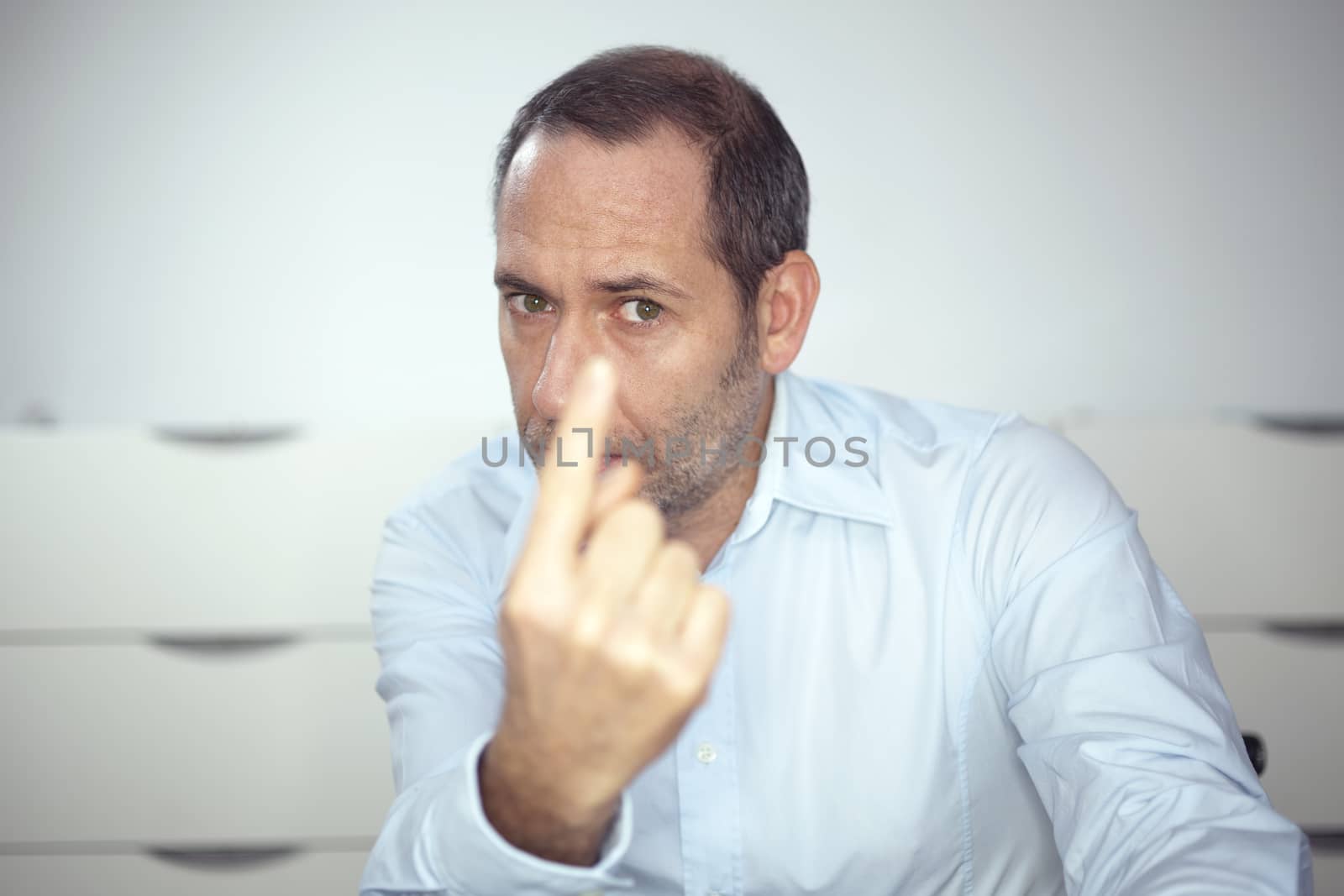 mature well dressed businessman is pointing into the camera