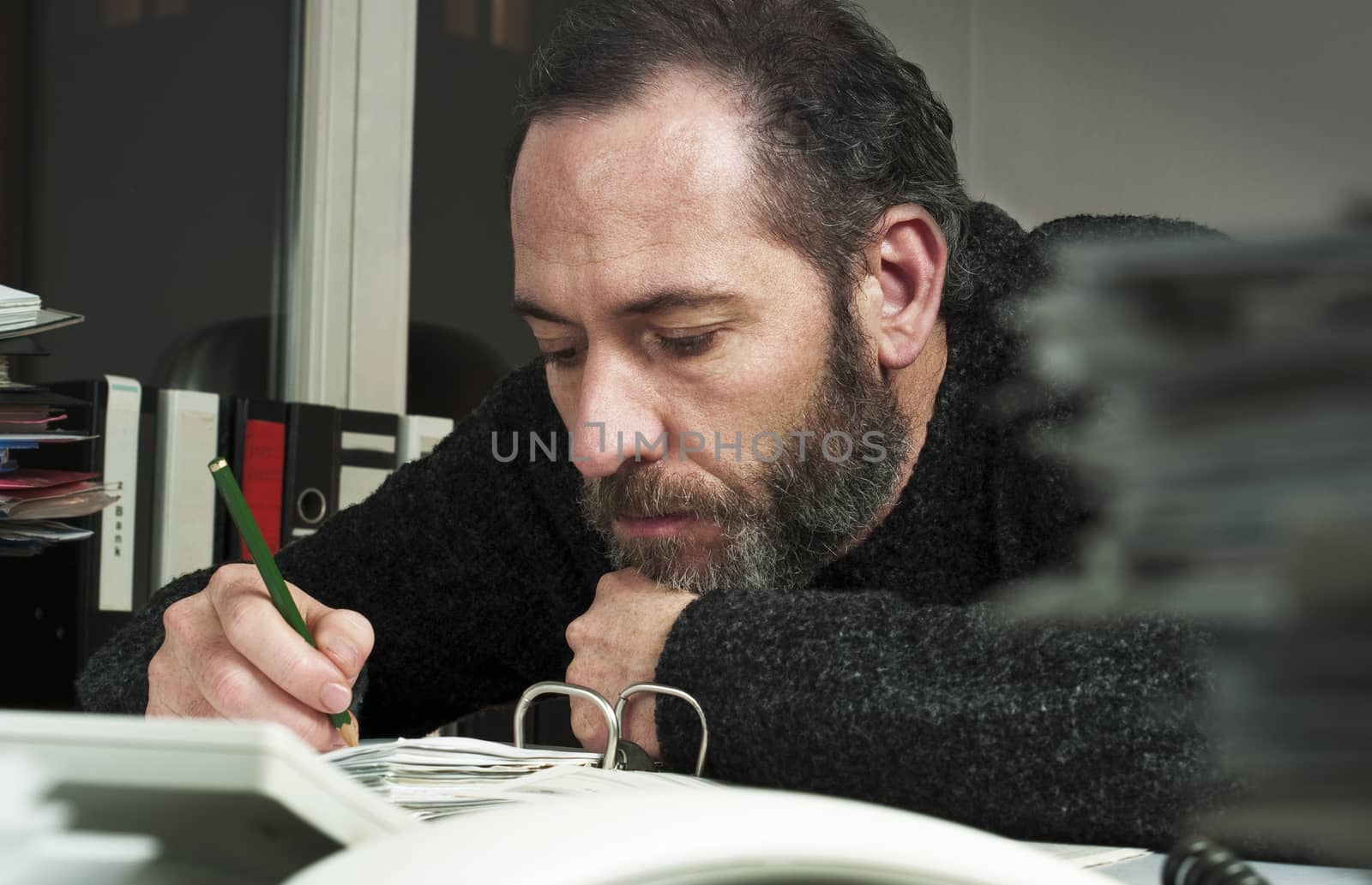 Mature businessman writing on papers at office-overworked at night time. Horizontal shot