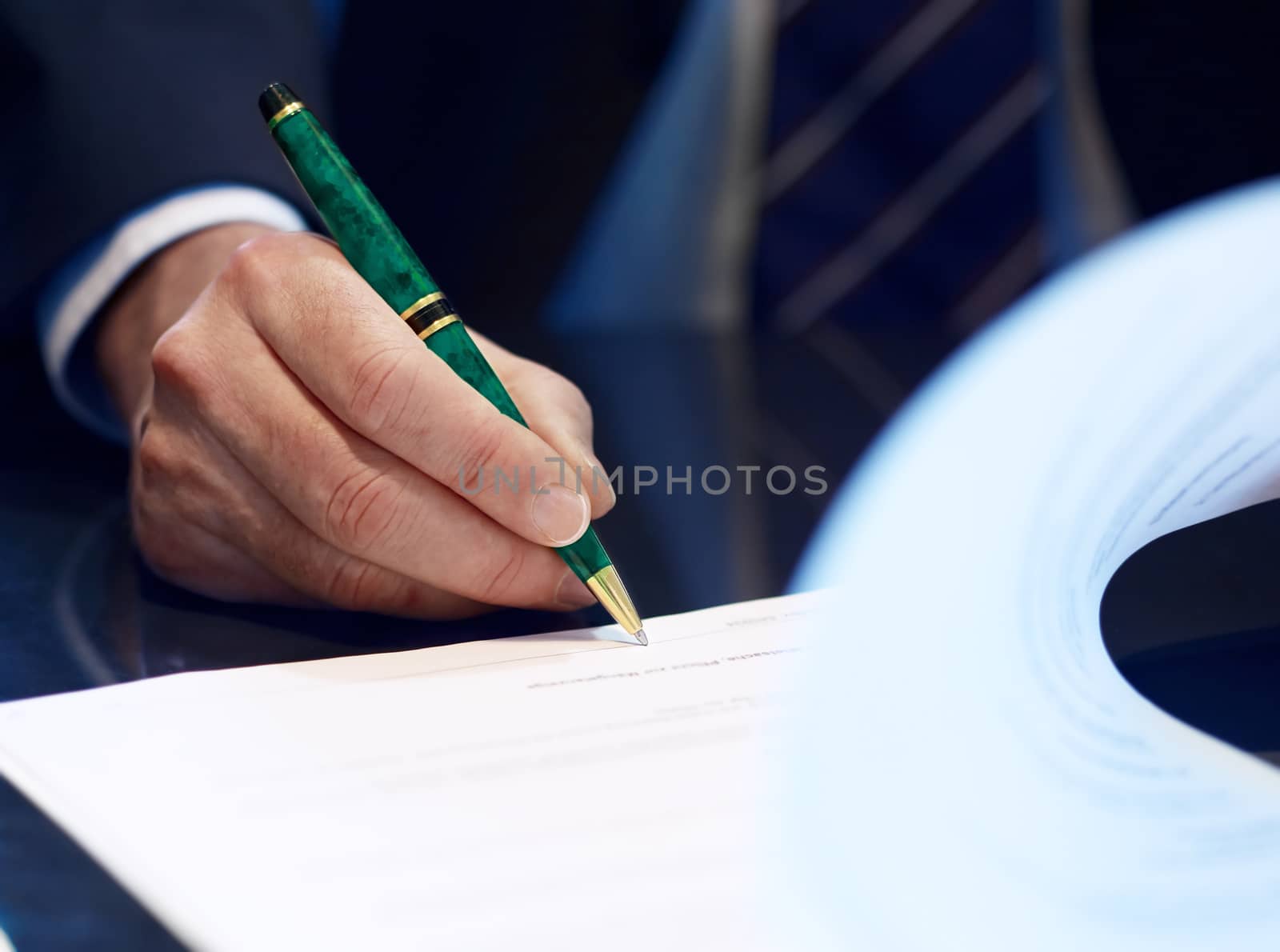 Businessman sitting at shiny office desk signing a contract with noble classic pen 