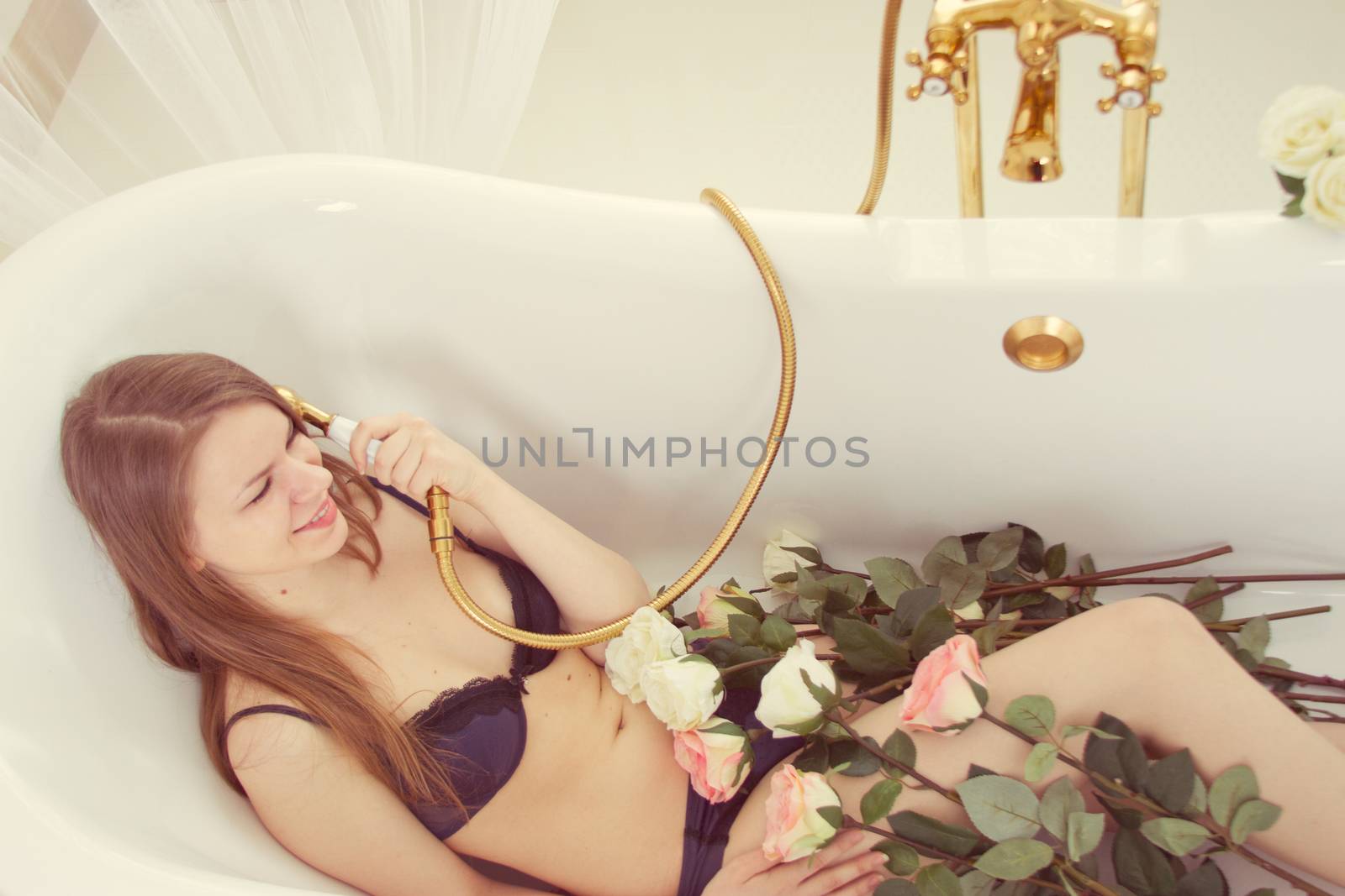 Girl in underwear lying in the bathroom with roses without water
