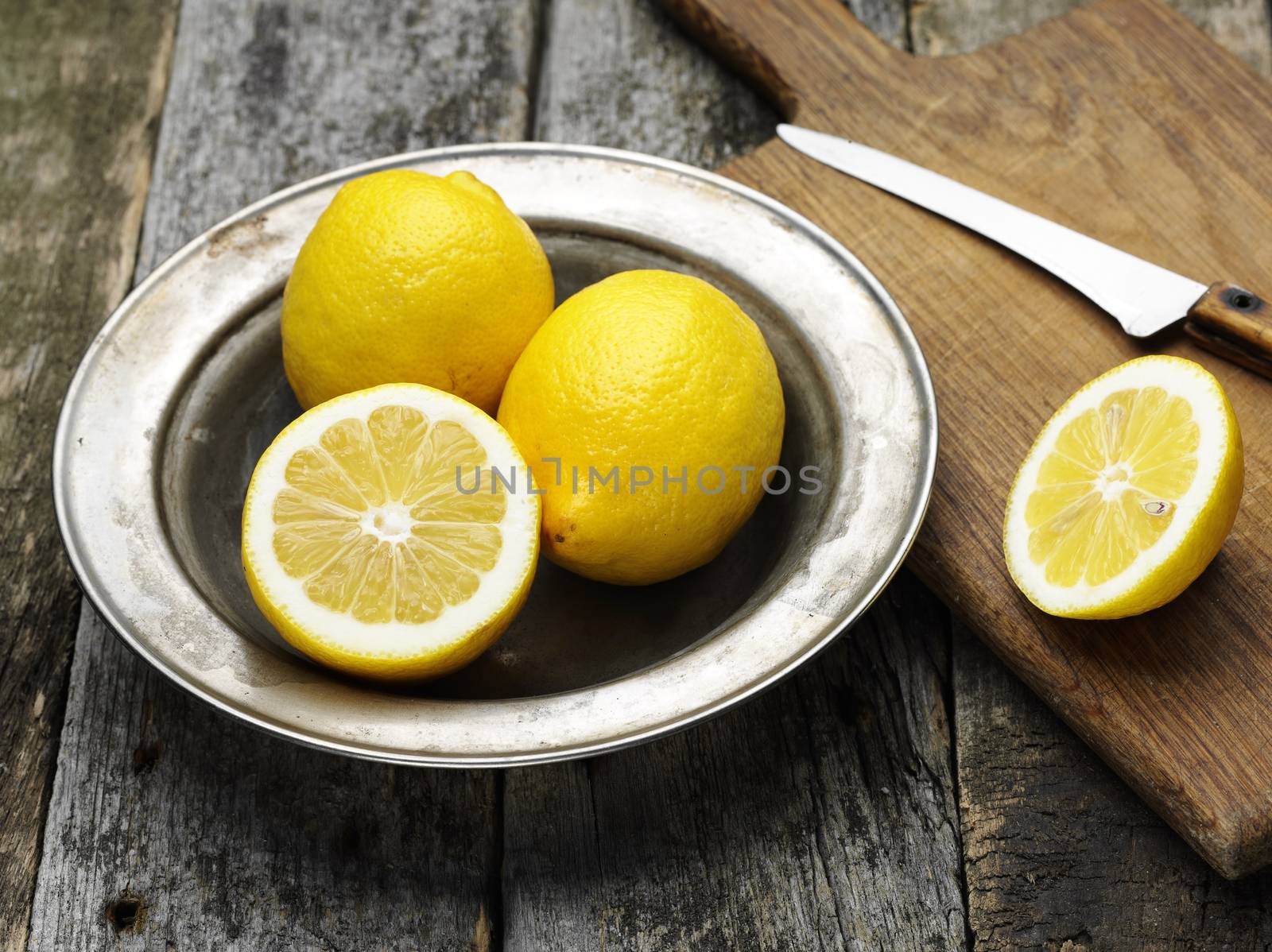 fresh ripe lemons in the steel plate on wooden board