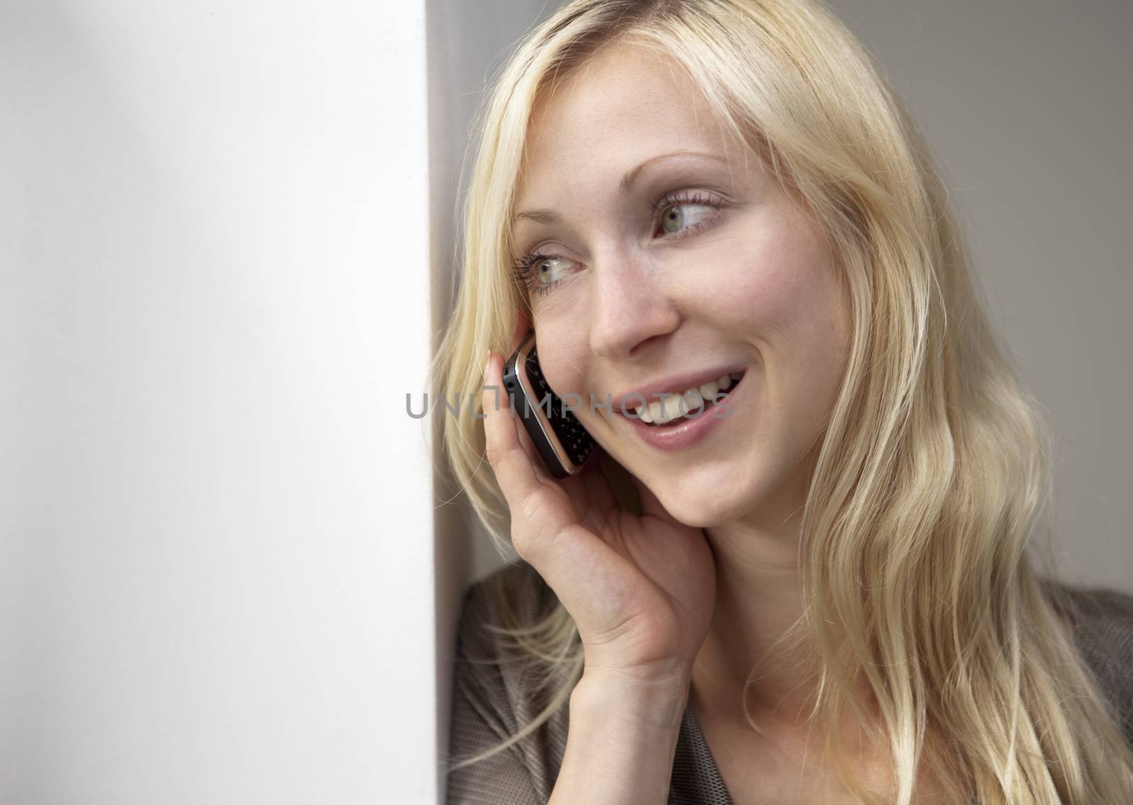 a young business woman on the phone, looking thru window, smiling