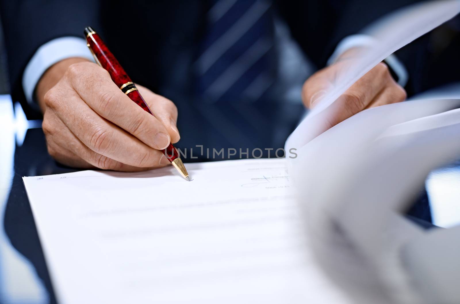 Businessman sitting at shiny office desk signing a contract with noble pen 