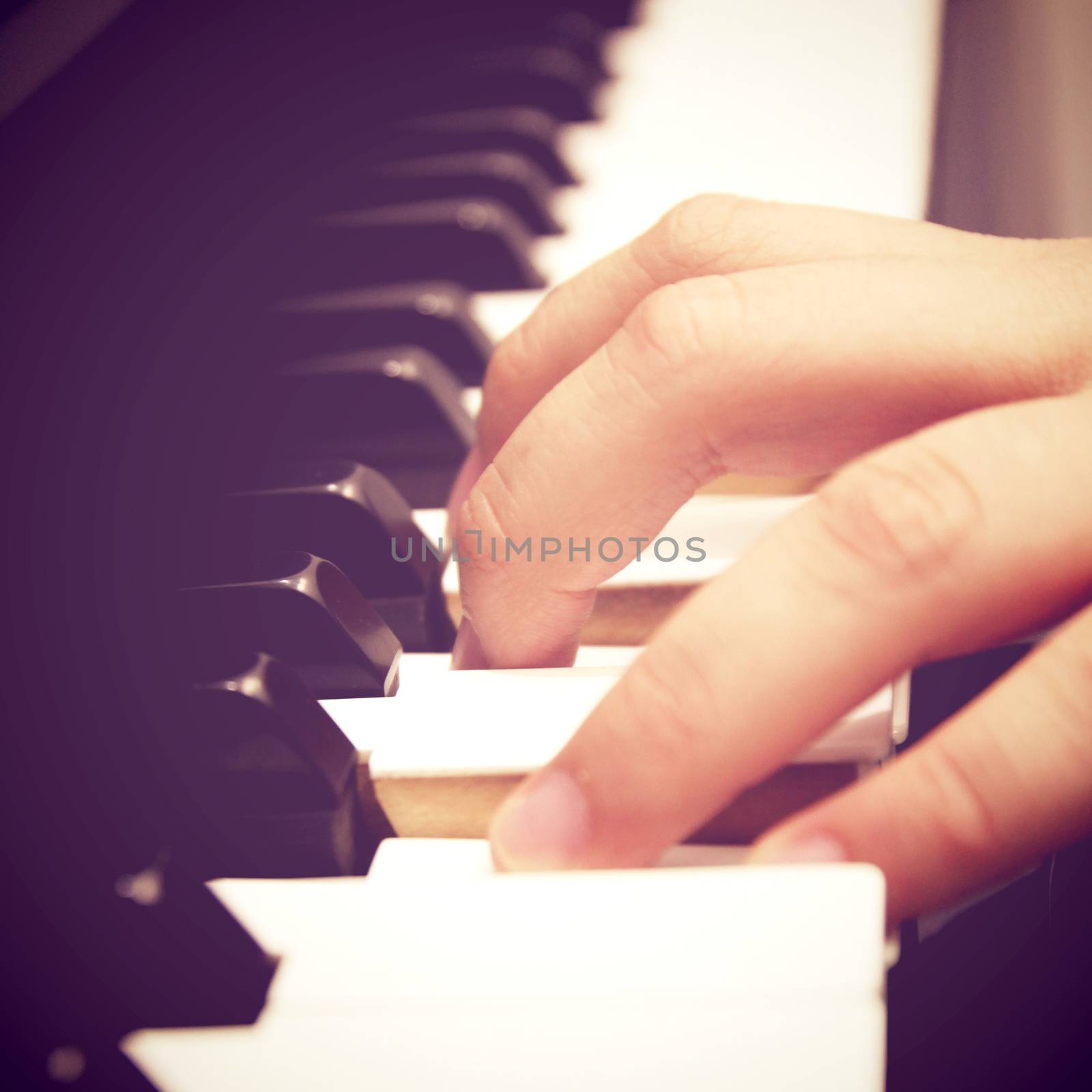 Close up of hand playing piano with retro filter effect