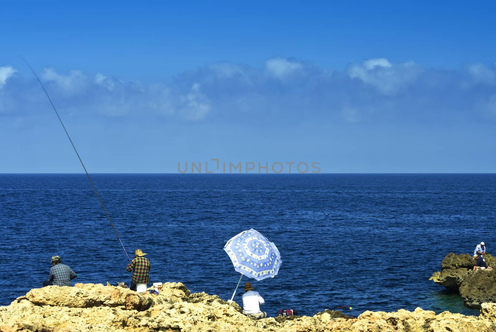 Rocky shore in the vicinity of Cirkewwa and a group of anglers - north-western Malta
