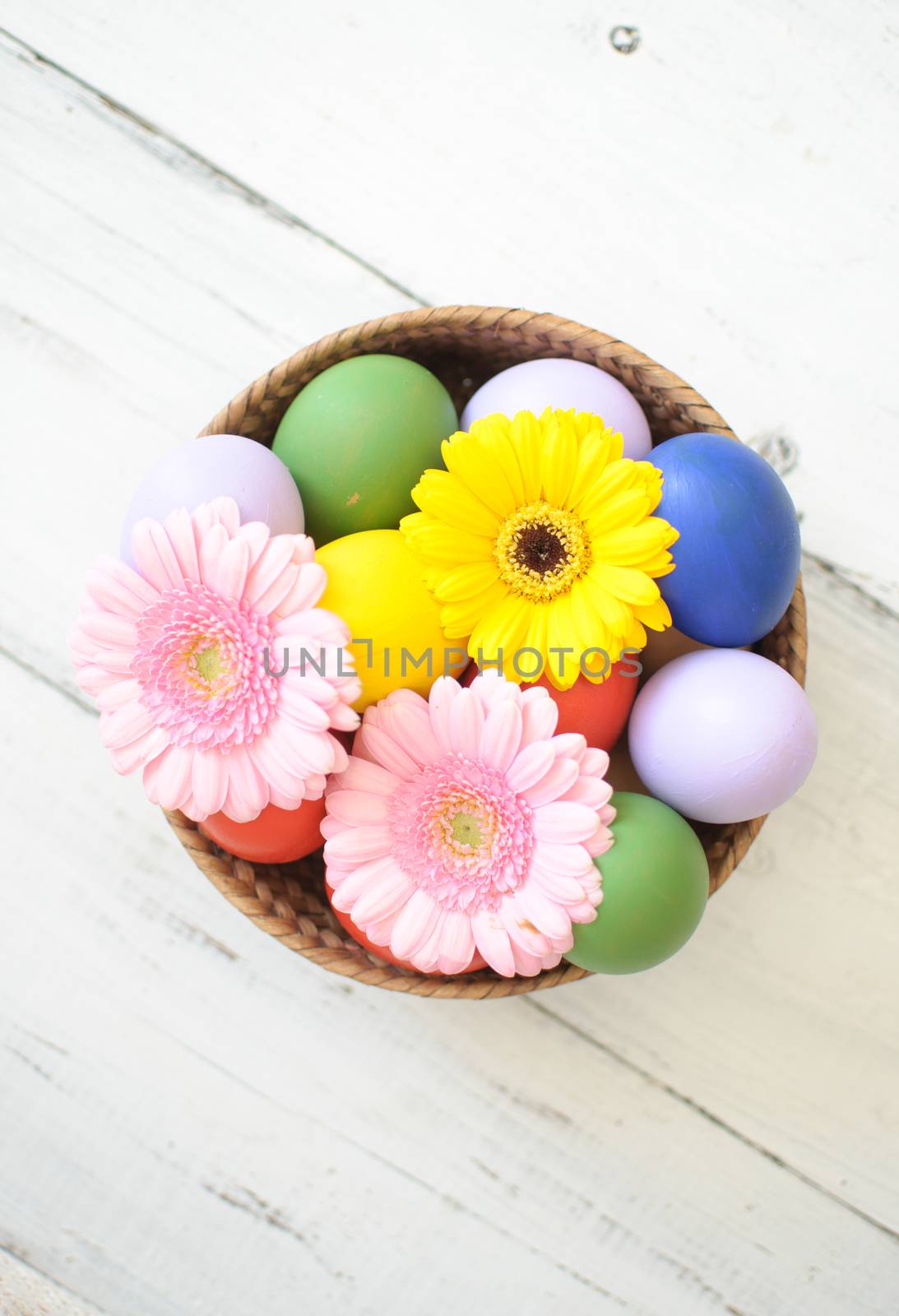 Easter eggs inside a wicker basket with daisies