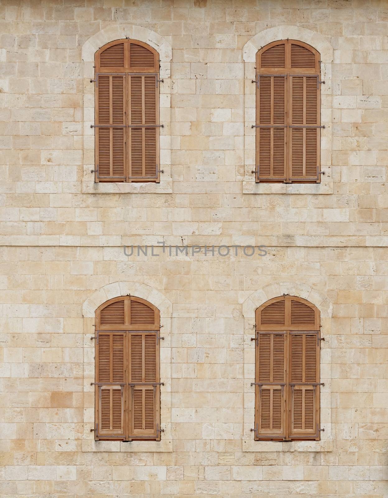 Wall of the old building with closed windows covered by wooden blinds