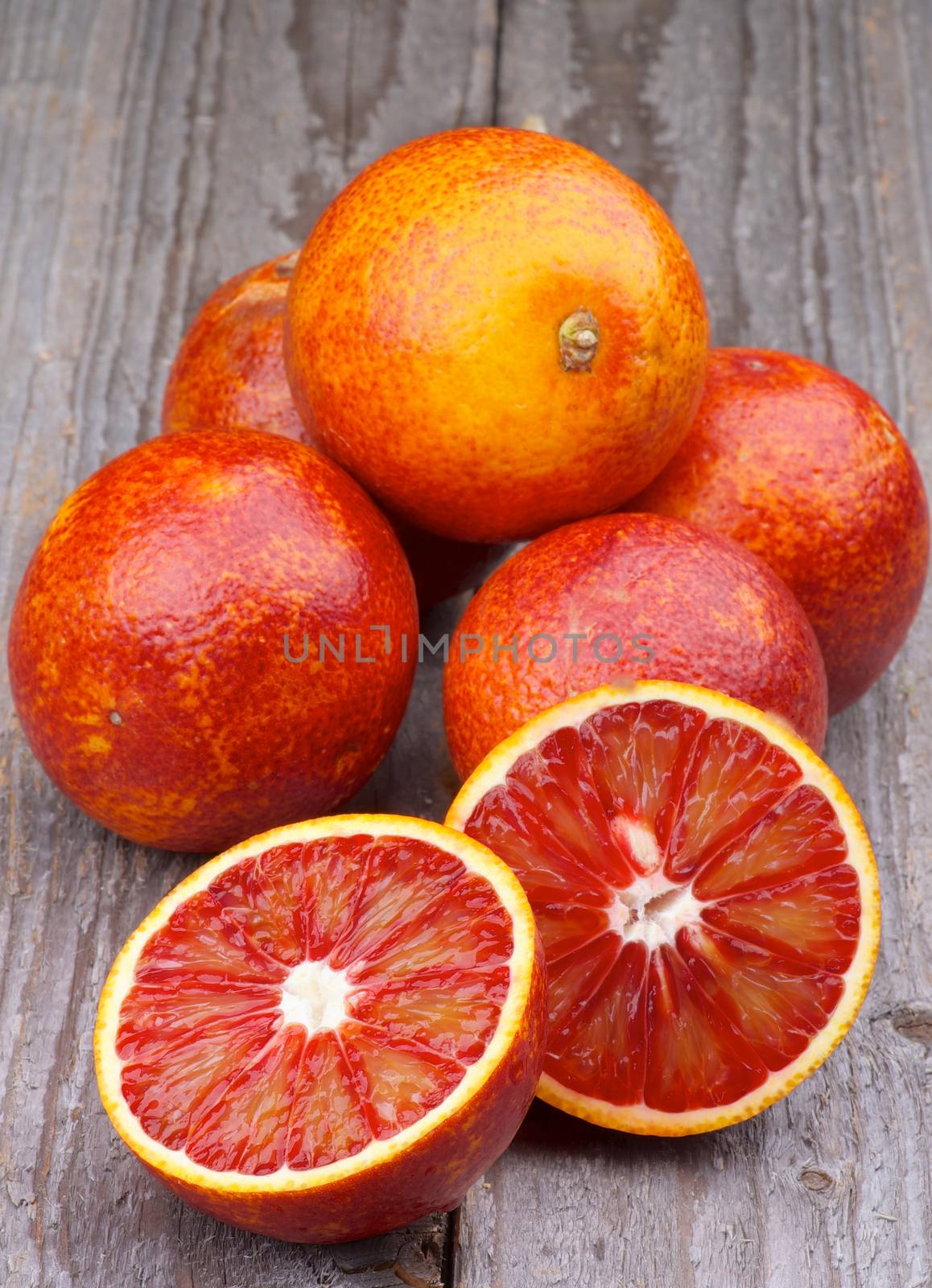 Heap of Ripe Blood Oranges with Two Halves isolated on Rustic Wooden background