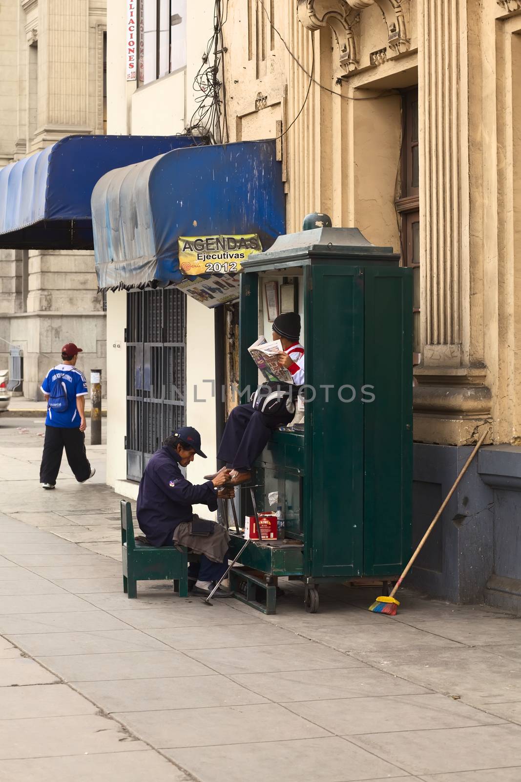 LIMA, PERU - JULY 21, 2013: Unidentified man cleaning the shoes of another person in the city center on July 21, 2013 in Lima, Peru. There are many people on the streets of Lima cleaning shoes.