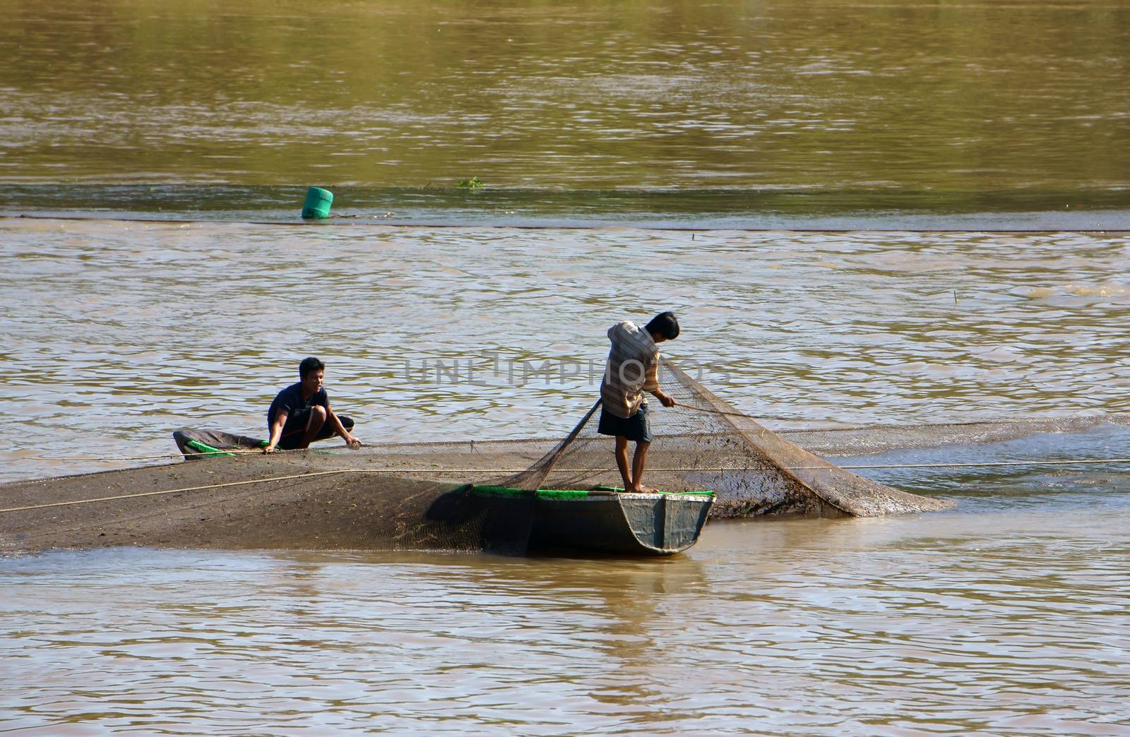 DONG THAP, VIET NAM- NOV 12: Two fisherman do fishing on river, he spread a net to catch fish, then pull the net and beat it with the rod to reject trash in Dong Thap, Viet Nam on Nov 12, 2013