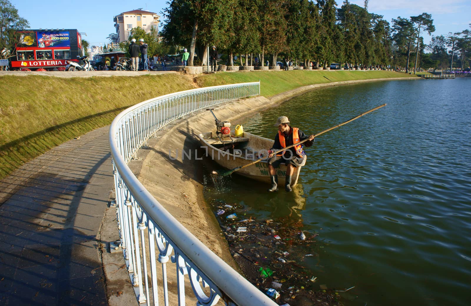 DA LAT, VIET NAM- DEC 29: Vietnamese sanitation worker working on Xuan Huong lake, he's  sit on boat and pick up rubbish from surface water to clean up the lake in Dalat, Vietnam on Dec 29, 2013